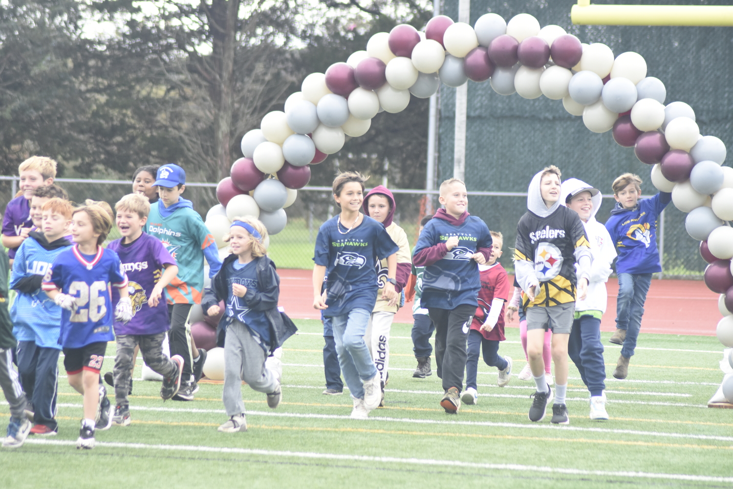 Kids from East Hampton's thriving youth flag football program, started by varsity head coach Joe McKee, run onto the field to welcome the varsity players.   DREW BUDD