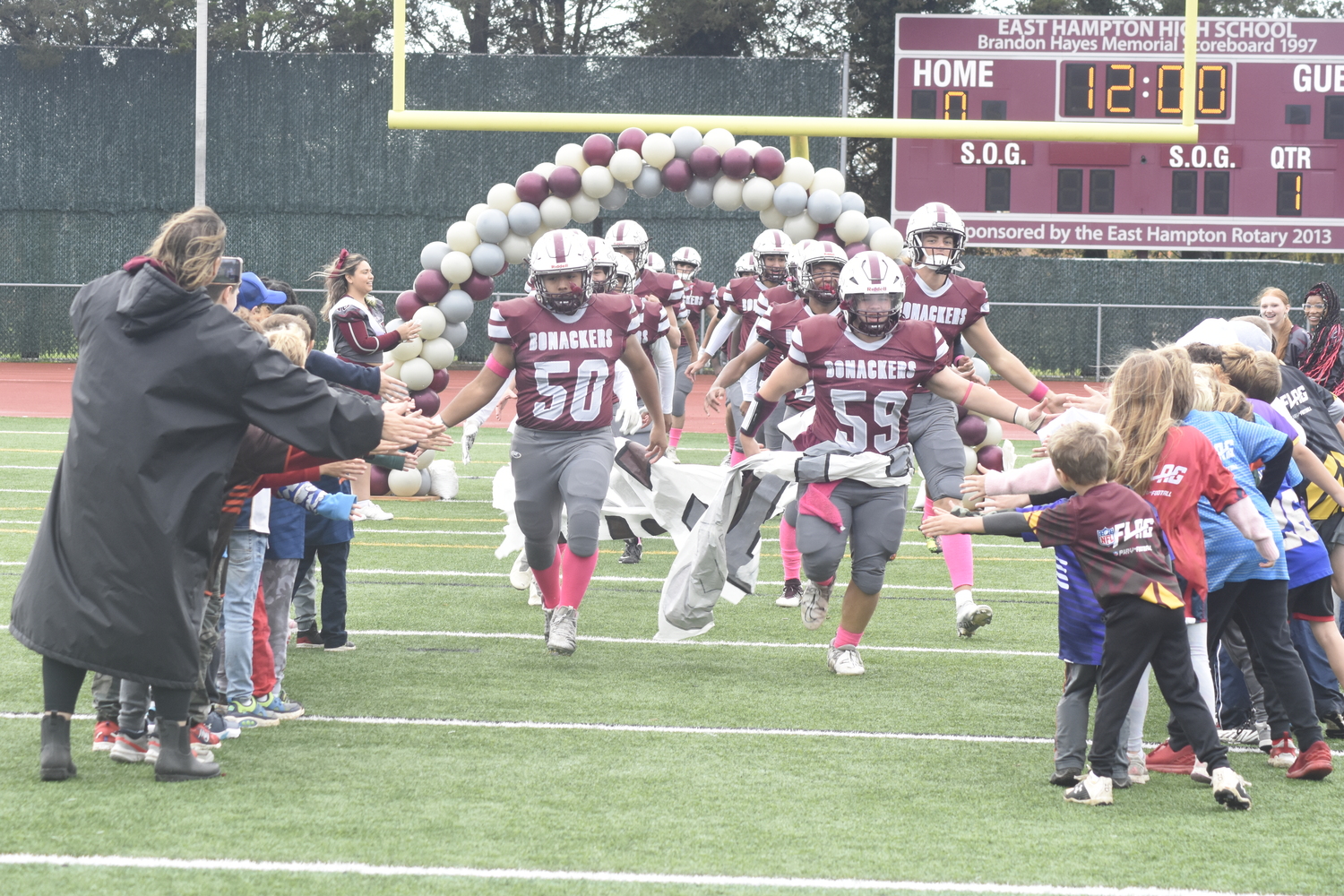 The Bonackers are welcomed onto the field by East Hampton's youth flag football players.   DREW BUDD