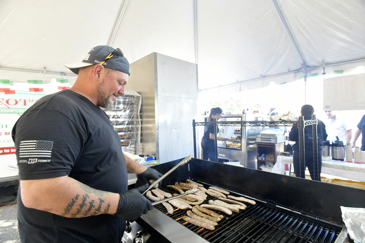 Bob Noti cooks up sausages in the Scotto's tent at the San Gennaro Feast of the Hampton on Saturday.