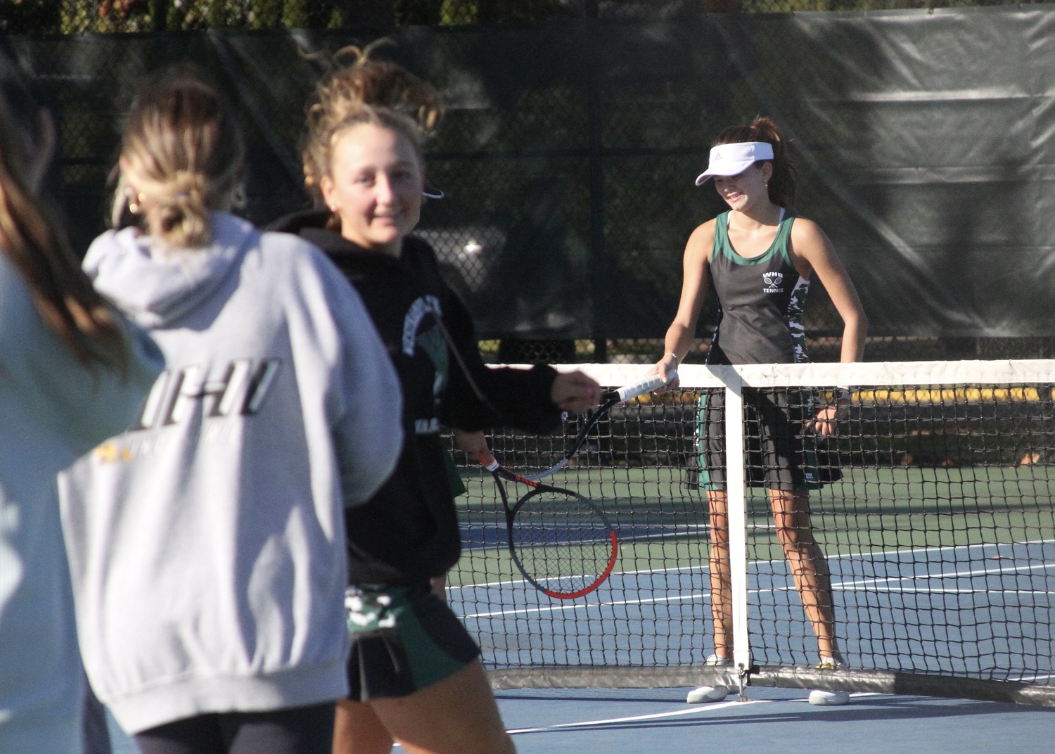 Sophomore Diana Elliott at the net with her challenger as her Westhampton Beach teammates storm the court to congratulate her on her win. DESIRÉE KEEGAN