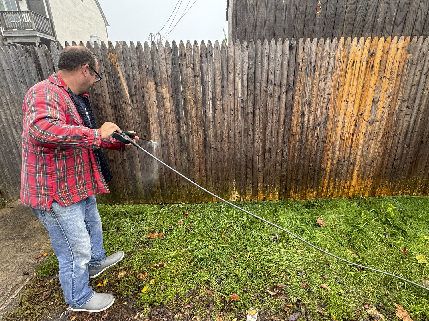 Former FDNY firefighter Morgan Neff power washing the swastikas off the fence at Naturally Good on Monday in Montauk.