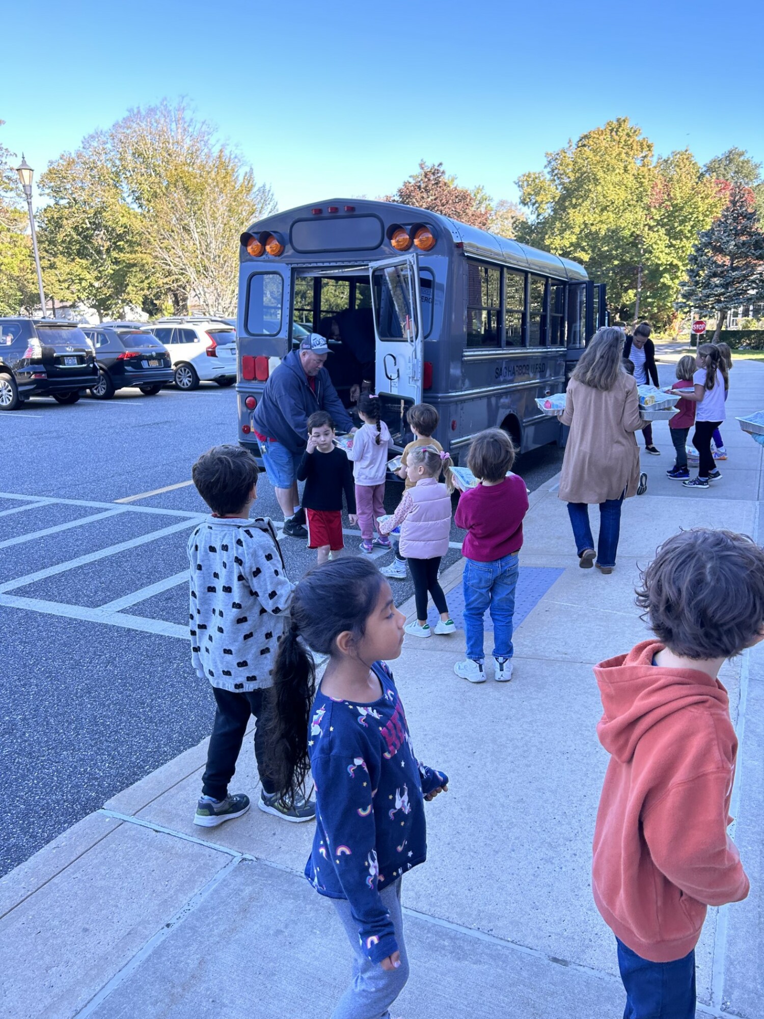 Sag Harbor Elementary School custodian, Mr. Bedell, school counselor Michelle Grant, and first grade teacher, Ms. Cohen assist the kindergarten and first graders with loading the minibus to deliver “Cake in a Pan” donations to the Sag Harbor Food Pantry. COURTESY SAG HARBOR SCHOOL DISTRICT