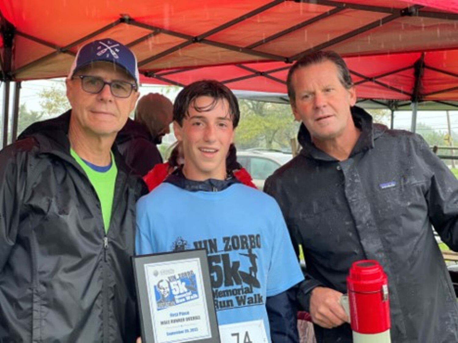 Steffi Vickers was the top finishing female in the Vin Zorbo 5K in Westhampton Beach on Saturday. Ben Grasso took the prize in the male division.  Bob Monpetit and Tom Day, right, both members of the Knights of Columbus Father Slomski Post, were the event organizers.  COURTESY GEORGE MOTZ