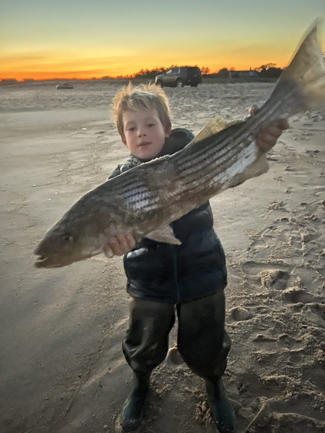 Ryder Nadal, 7, with a nice striped bass caught from the beach near Georgica Pond. 
LEE NADAL