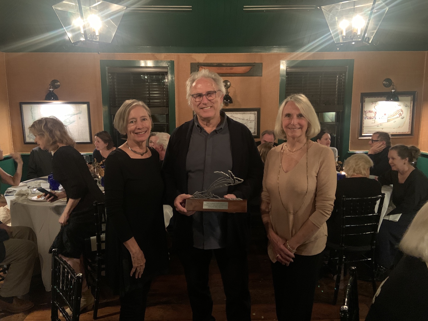 Eric Fischl, with the Sag Harbor Partnership's co-presidents, Susan Mead, left, and Jayne Young, was honored with the organiazation's Community Service Award at Baron's Cove on Sunday. STEPHEN J. KOTZ