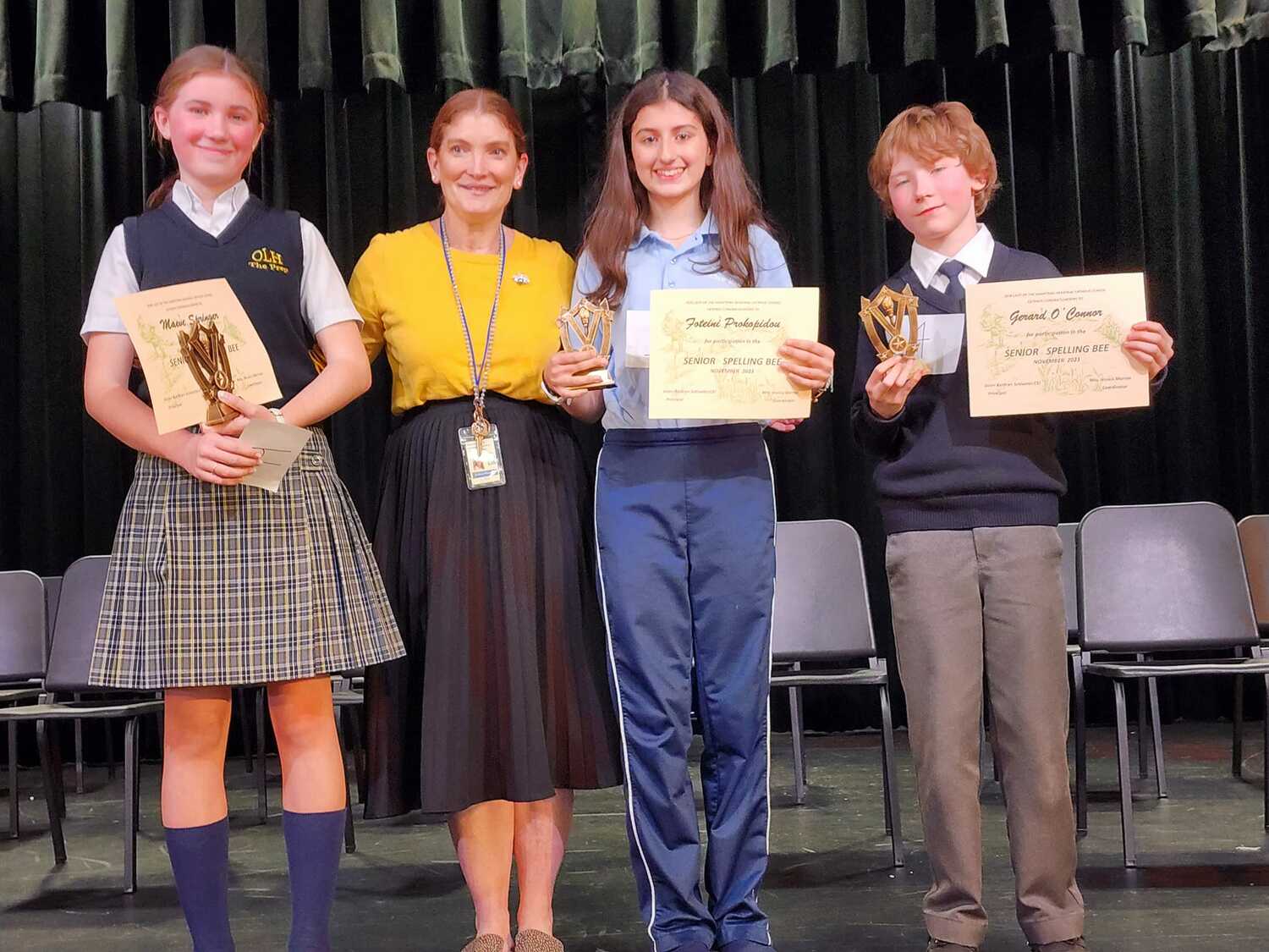 Our Lady of the Hamptons School's spelling bee winners, from lefit, Maeve Spring, third place; Foteini Prokopidou, first place; and Gerard o'Connor, second place, with bee coordinator Jessica Marron. COURTESY OUR LADY OF THE HAMPTONS SCHOOL