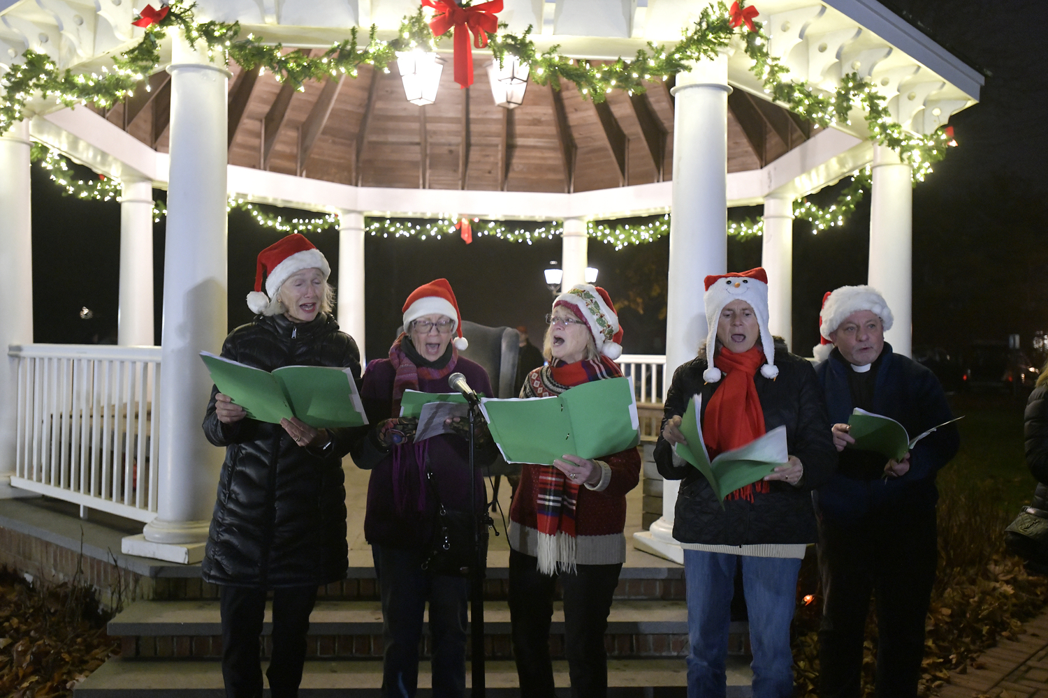 Carolers perform holiday songs at the gazebo on the village green on Saturday evening.