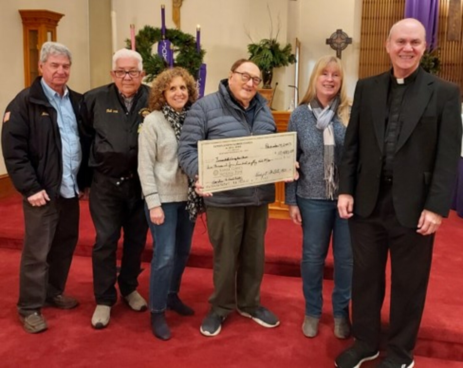 Representatives of three local service clubs gathered together at Immaculate Conception Church this past week to present the proceeds from their food pantry dinner, held recently at the church parish center. Presenting a check totaling $10,480.29 to new Immaculate Conception Church pastor Father Ken Grooms are, from left,  Mike Berdinka and Phil DeBrita, of the Knights of Columbus - Joseph Slomski Council of Westhampton; Rori Jones, representing the Kiwanis Club of Greater Westhampton; Jack Laadt of the Knights ; Beth Fanagan Hard, representing the Rotary Club of Westhampton; and Father Ken. The jointly sponsored event has provided much needed funds annually over the past 26 years to assist their neighbors in need. COURTESY GEORGE MOTZ