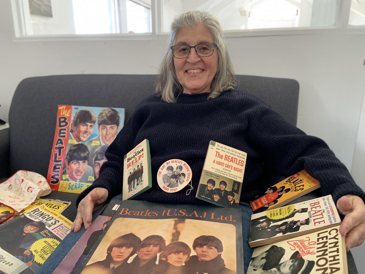 Cathy Worwetz with some of the Beatles memorabilia she collected during the height of Beatlemania, including, on her lap, a copy of the program from the band's 1965 performance at Shea Stadium. STEPHEN J. KOTZ
