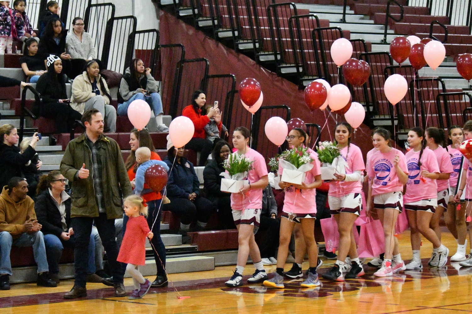 Brock Digger McMahon and his parents, Richie and Elisabeth McMahon, lead the Southampton girls basketball team onto the court during their Coaches vs Cancer game on Senior Night against Center Moriches on February 14.  MICHELLE MALONE