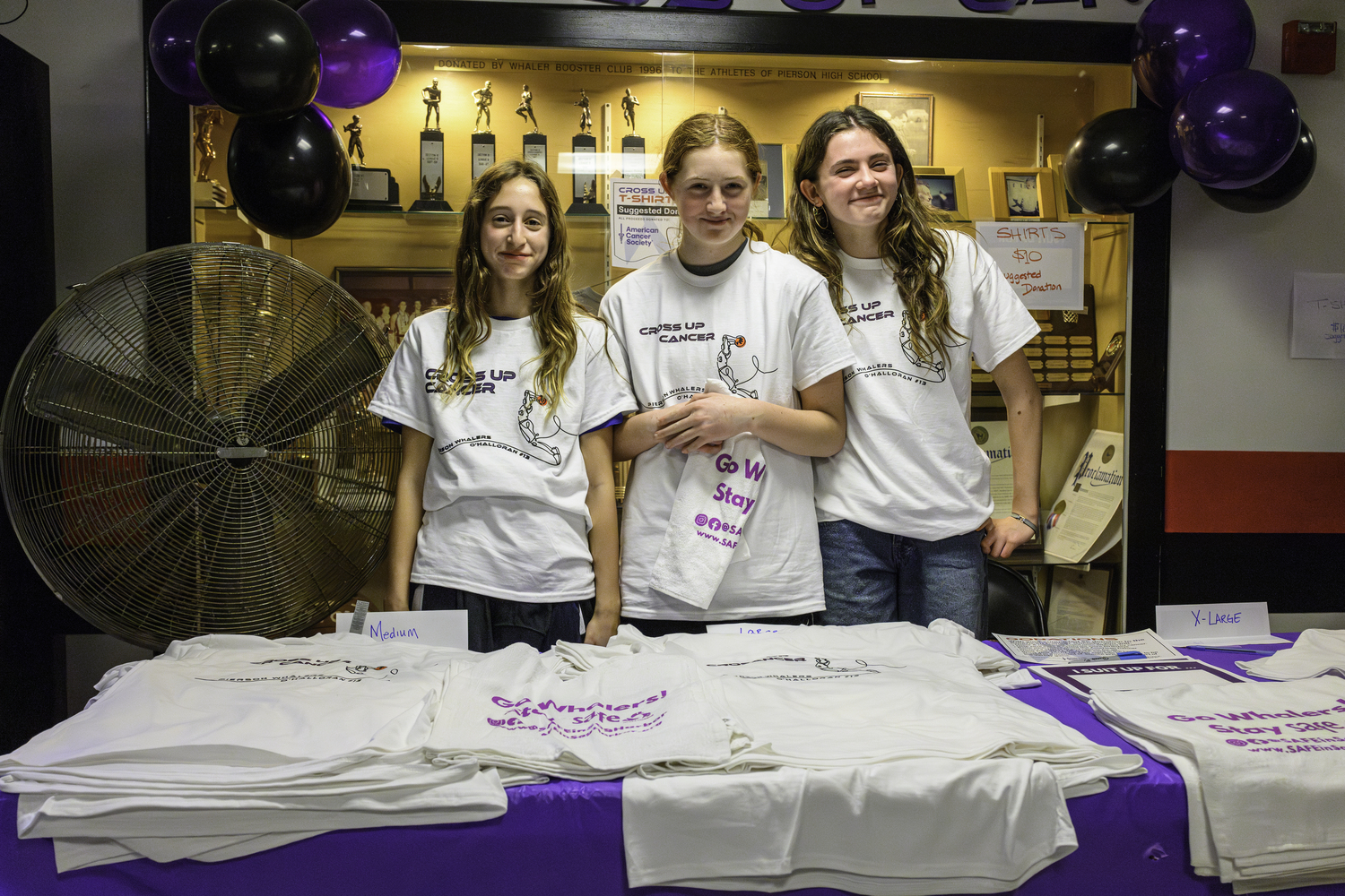 Students Molly Wolfson, left, Josie Mott and Sadie Culver sold T-shirts at Friday night's game with proceeds going to the American Cancer Society.  MARIANNE BARNETT