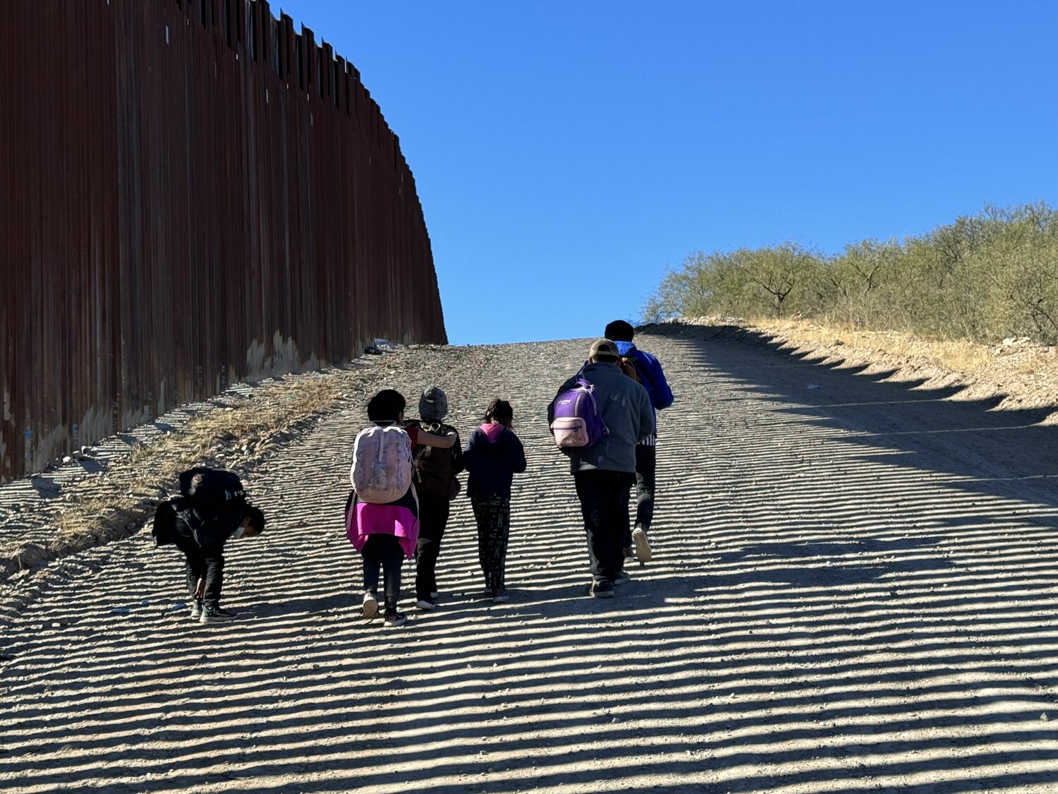 A family walks along the border wall outside Sasabe, Arizona. COURTESY ELISSA MCLEAN AND ANDY WINTER