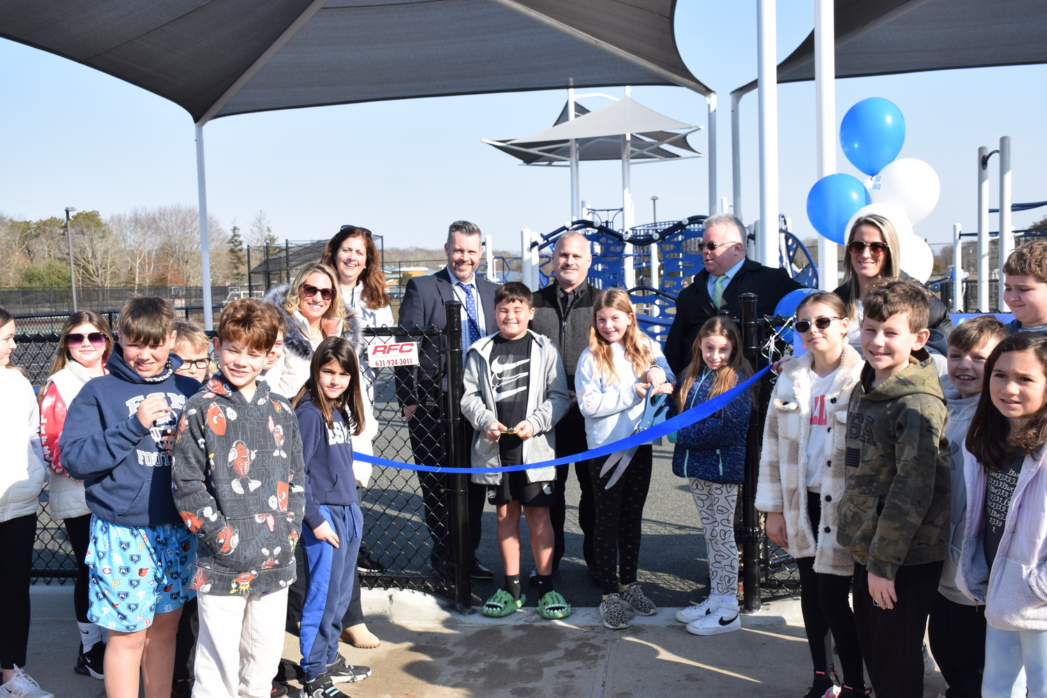 Center, from left, Eastport Elementary School Principal Thomas Fabian, Eastport-South Manor Board of Education Vice President Cristina Costanza, Board of Education President James Governali and Superintendent of Schools Joseph Steimel,  with students and faculty as they cut the ribbon to open the new playground. COURTESY EASTPORT-SOUTH MANOR SCHOOL DISTRICT