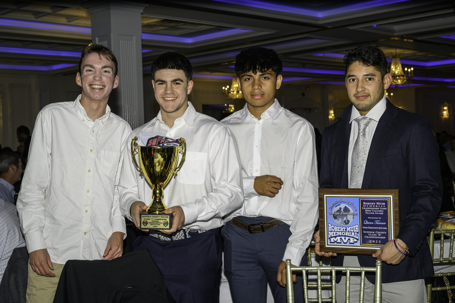 Ryder Esposito, left, Gus Hayes and Wilmer Reyes with the team's championship trophy with head coach Luis Aguilar holding the MVP plaque for Quinn Tanner.   MARIANNE BARNETT