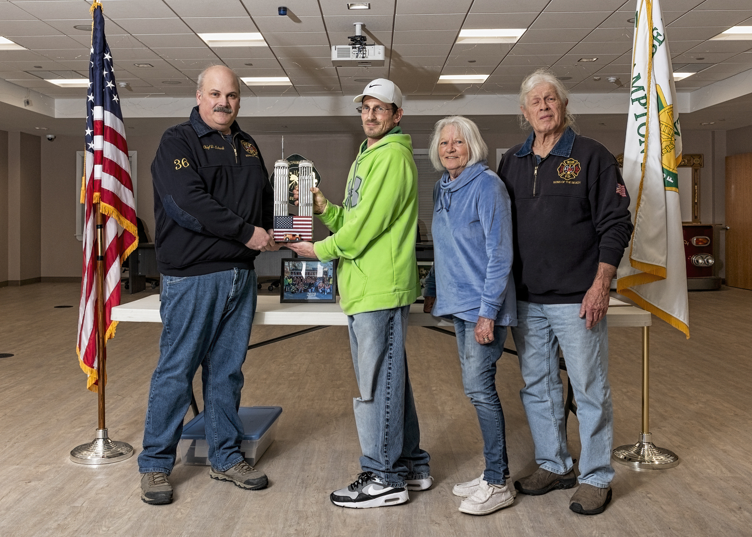 Brian Hoyle, second from left, presented Chief Darryl Schunk, left, with a metal sculpture he created depicting the World Trade Towers. Juniors' advisors Cody and Paul Hoyle are on the right. COURTESY WESTHAMPTON BEACH FIRE DEPARTMENT