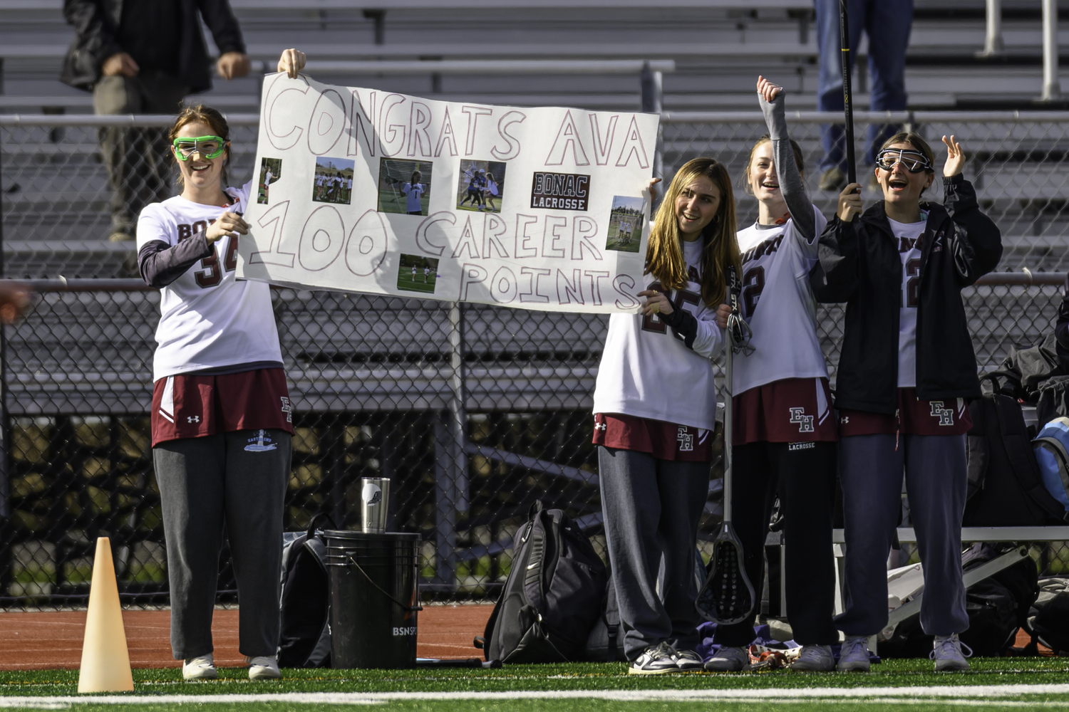 Ruby Tyrell, left, and fellow teammates hold up a sign marking Ava Tintle's career 100th point that she recorded in last week's victory over Southampton.  MARIANNE BARNETT