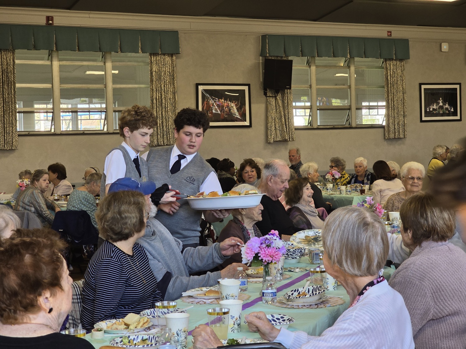 Our Lady of the Hamptons School Prep 8  students Ignatius Fulweiler and Abel Fernandez served senior citizen guest at a recent luncheon. COURTESY OUR LADY OF THE HAMPTONS SCHOOL