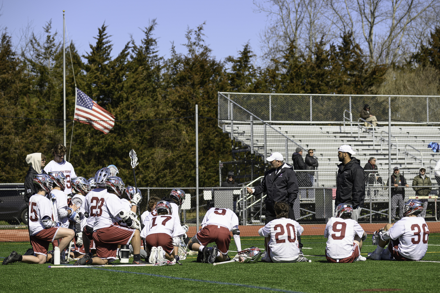 Coaches Matt Babb and Jaron Greenidge speak to their players at halftime, as the American flag in the background is at half mast honoring NYPD police officer Jonathan Diller who was killed last week and was laid to rest on Saturday.   MARIANNE BARNETT