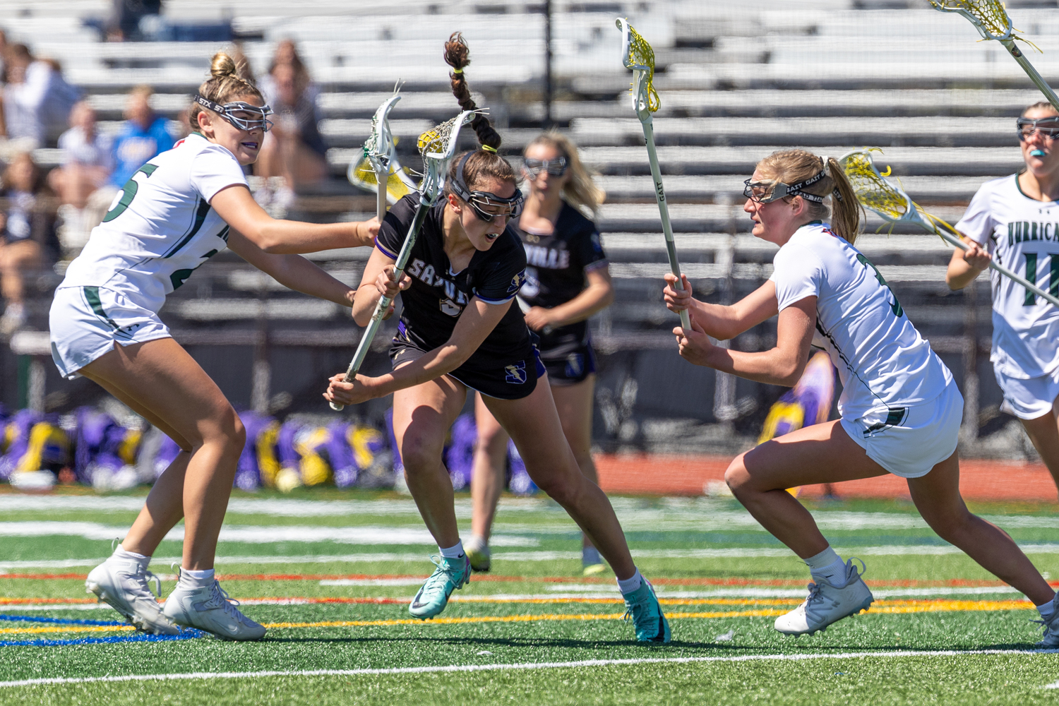 Senior defender Gabby Wendel and junior midfielder Lily Graves sandwich a Sayville opponent during a 9-5 loss on April 26. RON ESPOSITO