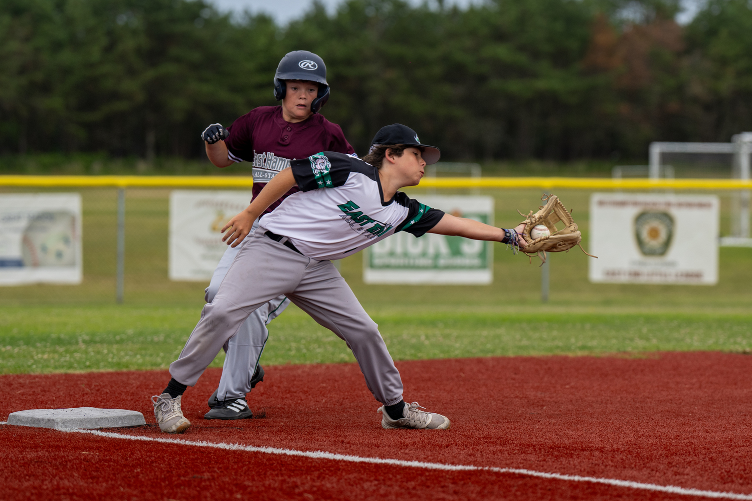 Ryan Flynn catches the ball at third base with an incoming East Hampton base runner.   RON ESPOSITO