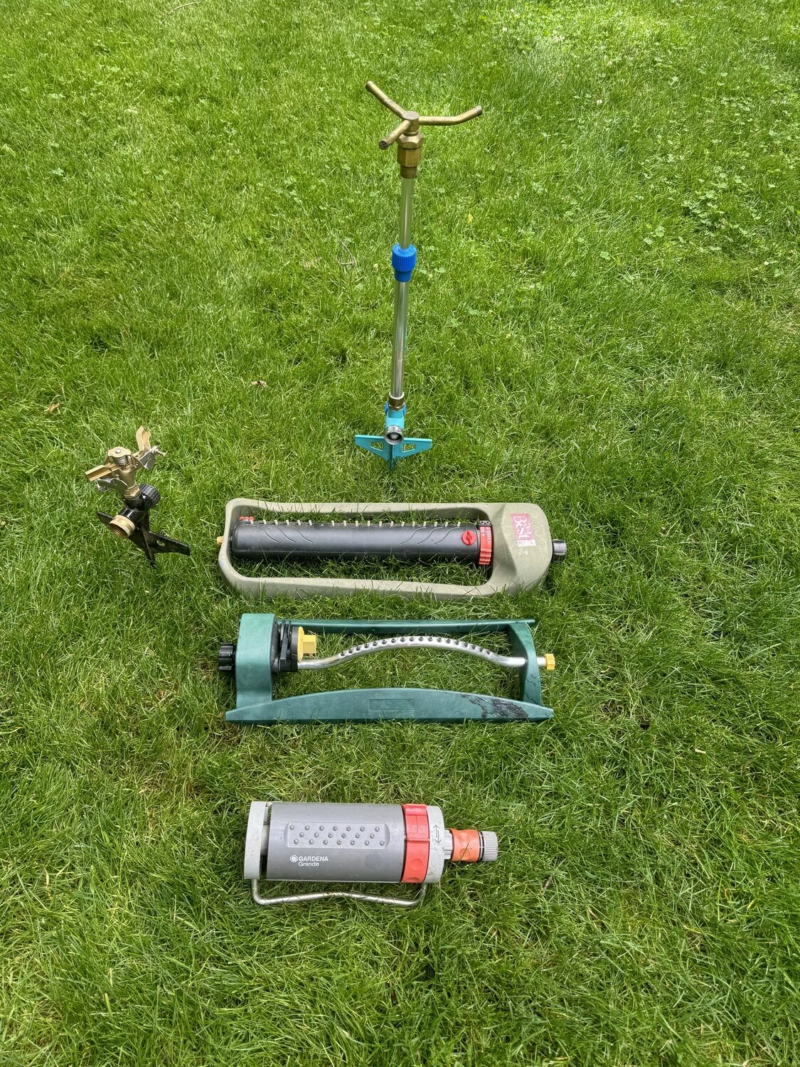 At the top is a spinning sprinkler that can be used in a garden with shorter plants or a small lawn area. The diameter of the area watered is controlled by adjusting the water flow at the hose bib. Below are three types of oscillator sprinklers. Note the yellow end of the oscillator bar on the right. Unscrewing this end cap reveals a clean-out tool for the orifices. All three are adjustable to manage the rectangle watered, and more expensive ones allow right and left adjustments. On the left is a ground-spike impact sprinkler. Good for seedling beds or lawns.  ANDREW MESSINGER