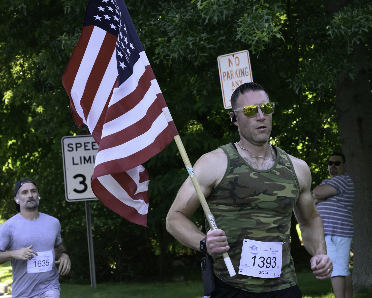 Gregory Waxman runs with the flag at the start of the Shelter Island 10K.   MARIANNE BARNETT