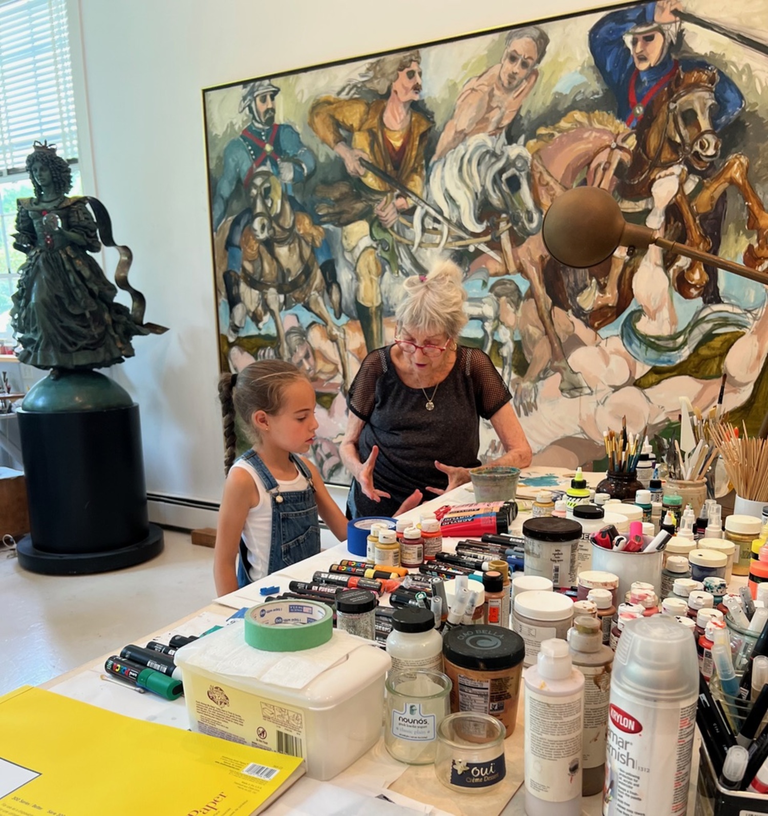 Audrey Flack, at age 92, teaches a young fan, Gia Rozenberg, about art against a backdrop of her painting, 