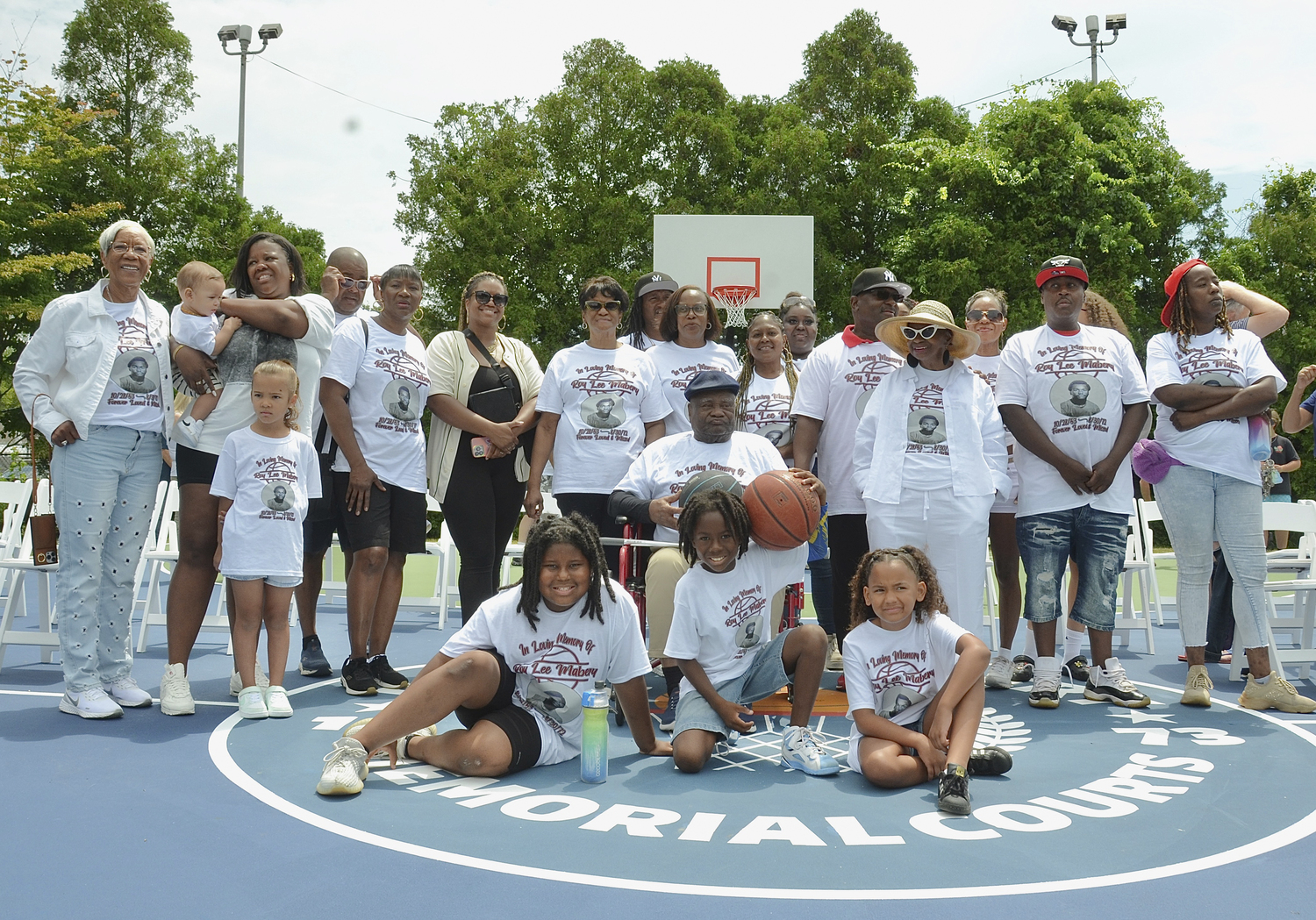 Roy Lee Mabery's father, Gilbert Mabery, center, was surrounded by family and friends during Saturday's ceremony to dedicate the new basketball courts in Herrick Park to the late student-athlete. KYRIL BROMLEY