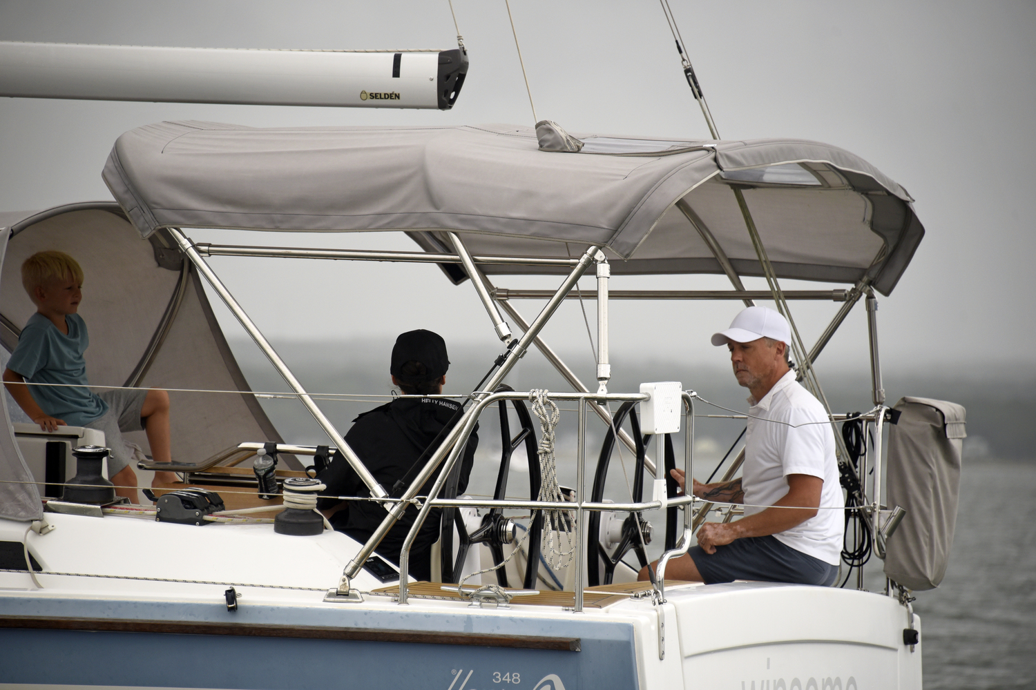 Sails yet to be hoisted, Gregory Thrope relaxes at the wheel of his Hanse 348 Winsome as his son looks on from under the protection of the dodger.  MICHAEL MELLA