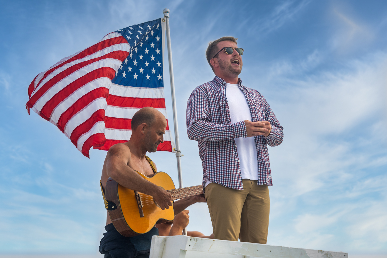 Kevin Quinn sings the national anthem before last week's Southampton Town lifeguard tournament, with guitar played by Dave Riley and Caleb Atkins-Barnes holding the flag.   RON ESPOSITO