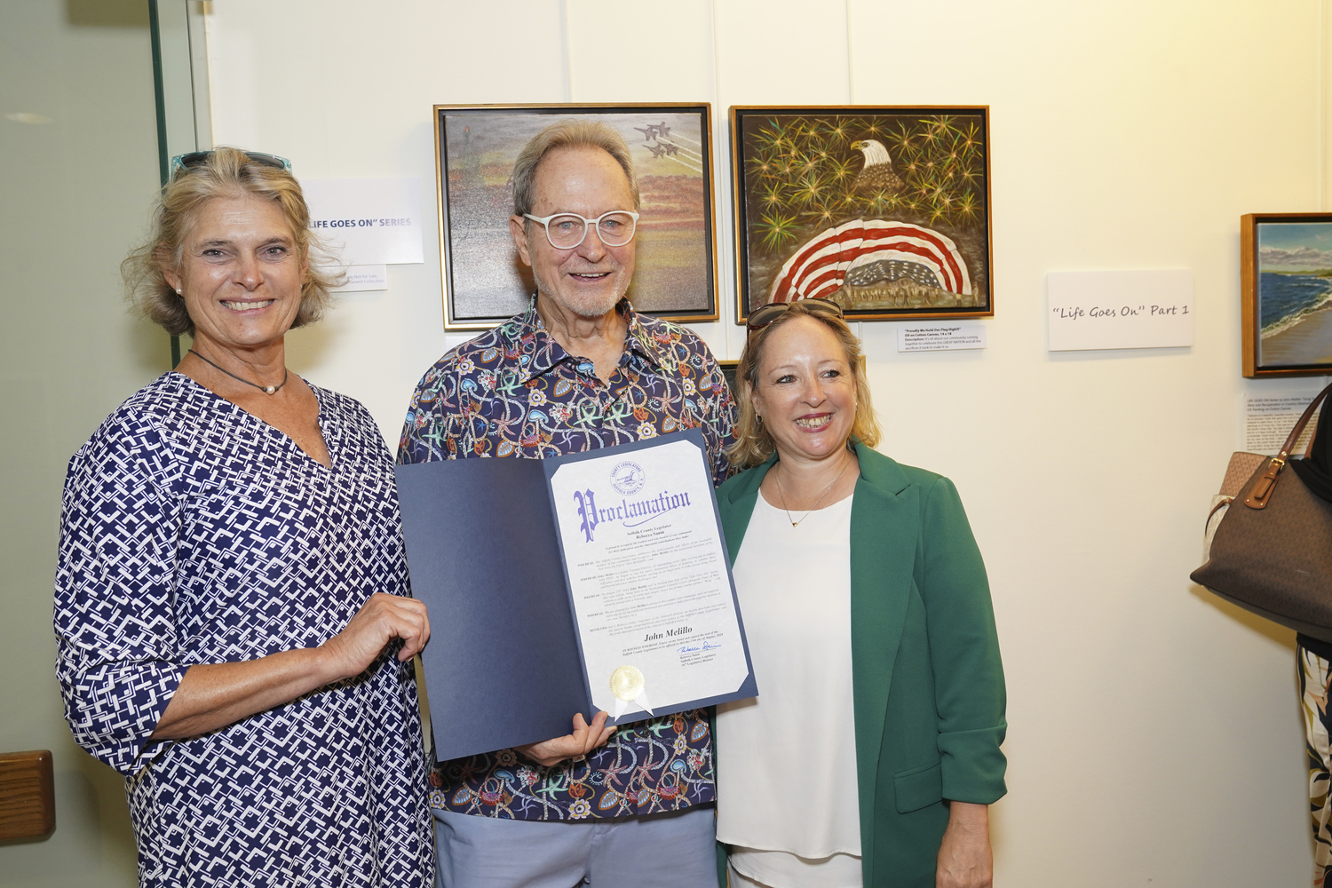 Suffolk County Legislators Anne Welker and Rebecca Sanin Legislators present Vietnam Veteran and artist John Melillo with a proclamation at his Life Goes on Part 4 art show at the Southampton Cultural Center on August 15.     COURTESY BETH MELILLO