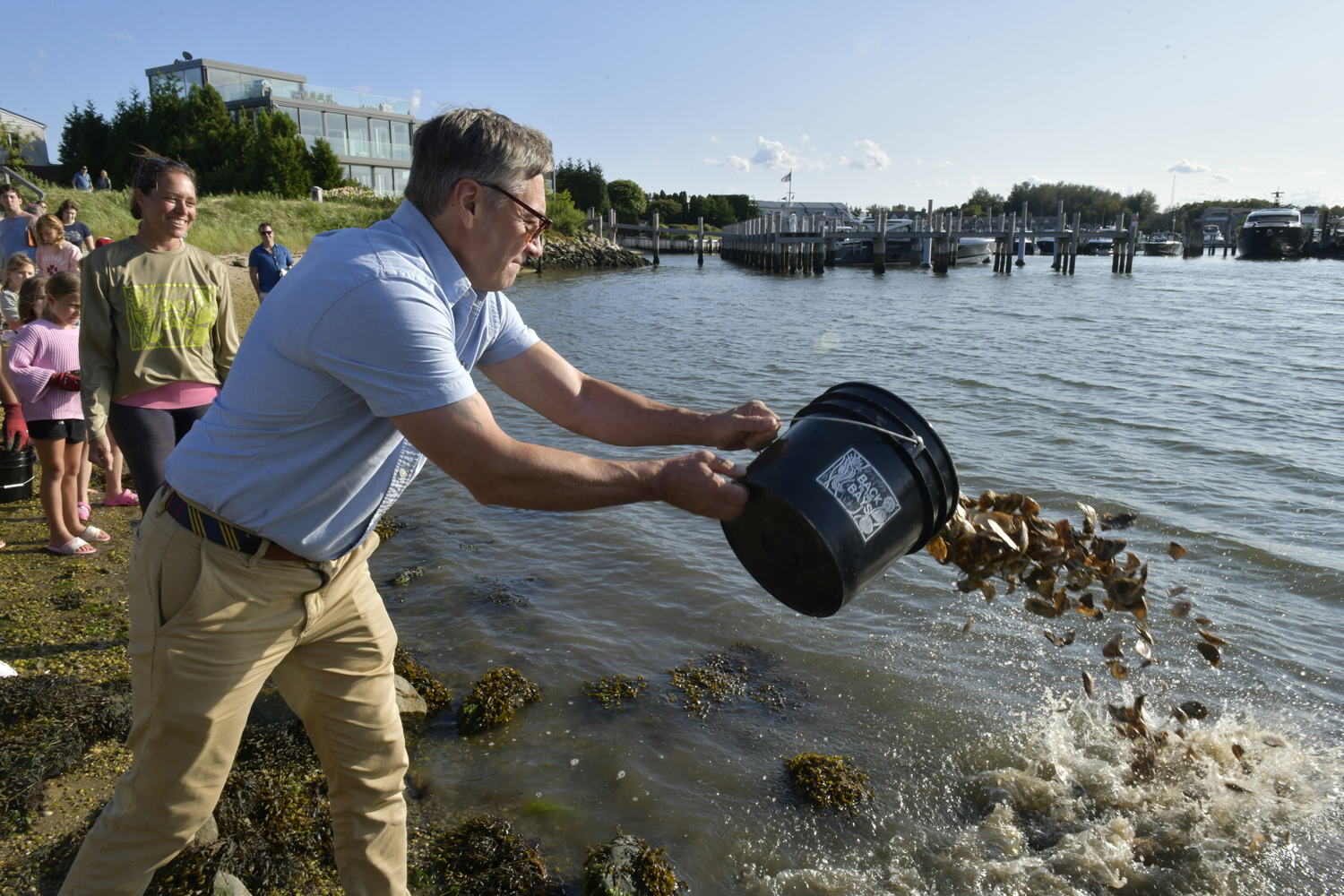 Sag Harbor Mayor Tom Gardella throws oyster seedling into the bay at Steinbeck Park.  DANA SHAW