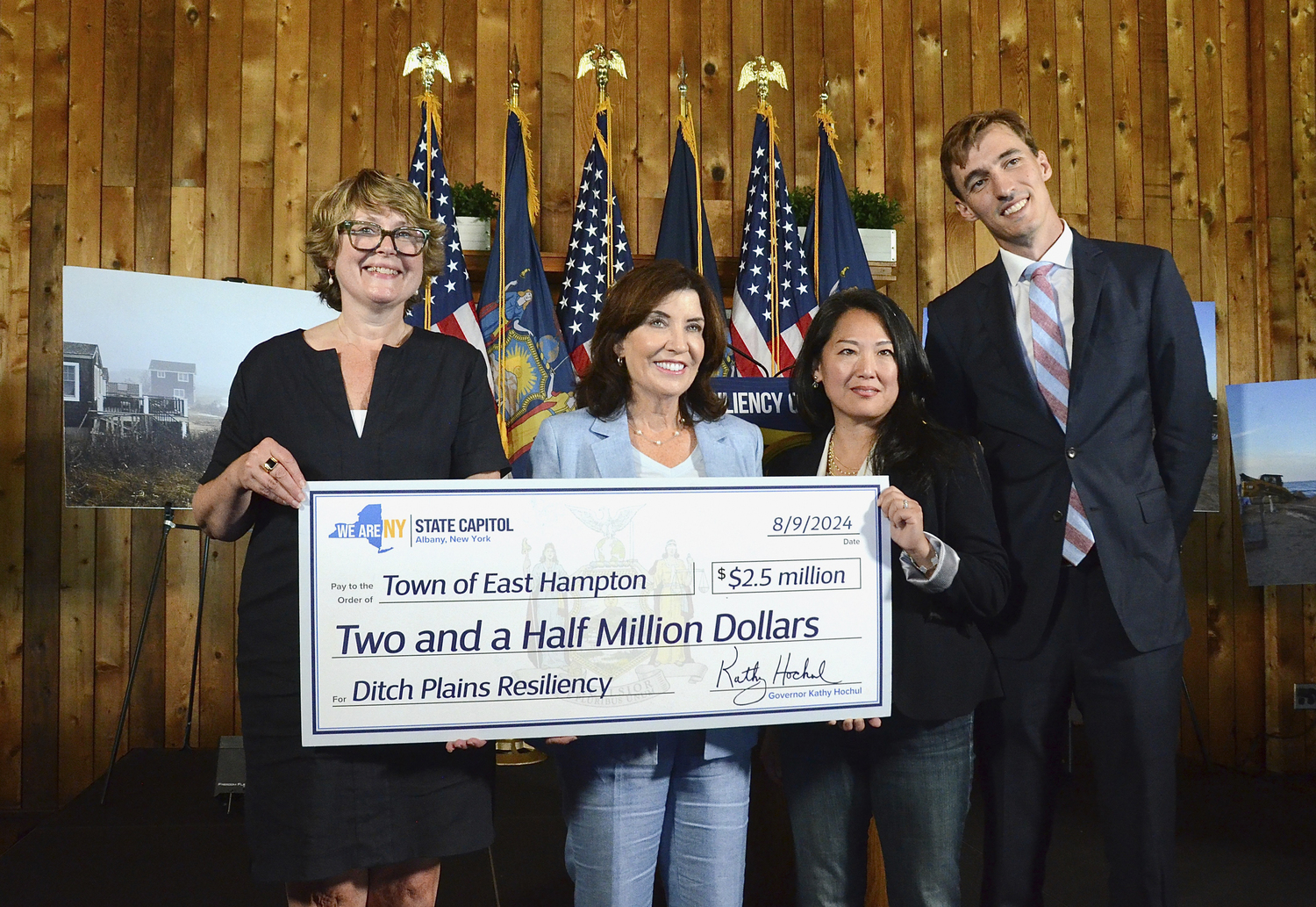 East Hampton Town Supervisor Kathee Burke-Gonzalez, Gov. Kathy Hochul, Kay Tyler of Concerned Citizens of Montauk and Leo Daunt of the Montauk Chamber of Commerce hold the ceremonial $2.5 check to be allocated to dune restoration at Ditch Plains in Montauk.      KYRIL BROMLEY