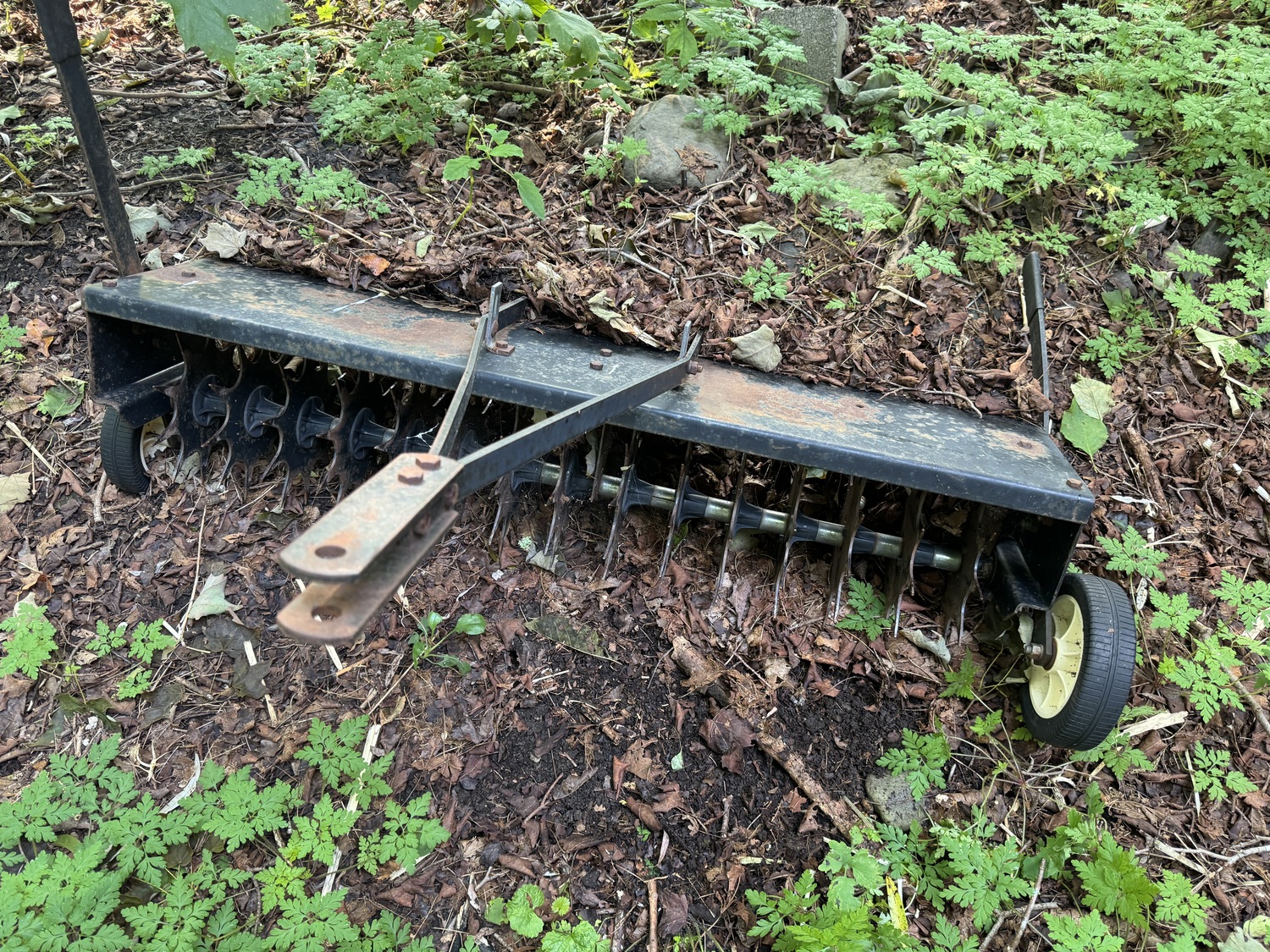 This is my 4-foot-wide tine/spike aerator that I use on the lawn prior to overseeding.  Concrete blocks are added to the tray on top for an extra 50 pounds of weight.  When the retractable wheels are raised the tines can make holes in the sod a few inches deep.  Pulled by a garden tractor or riding mower, it’s not nearly as good an aerator as the type that removes and drops 3-inch pugs of soil (available at rental stores).  ANDREW MESSINGER