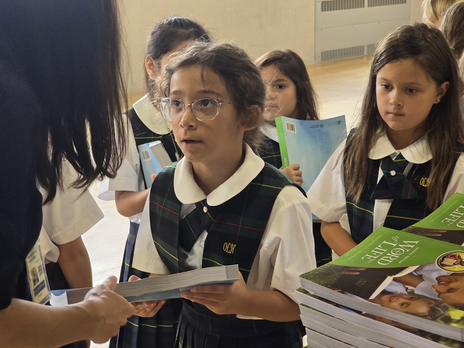 Our Lady of the Hamptons School second-graders Emma DiFiglia  and Parissa Weglein receive their religion books on the first day of school last week. COURTESY OUR LADY OF THE HAMPTONS SCHOOL