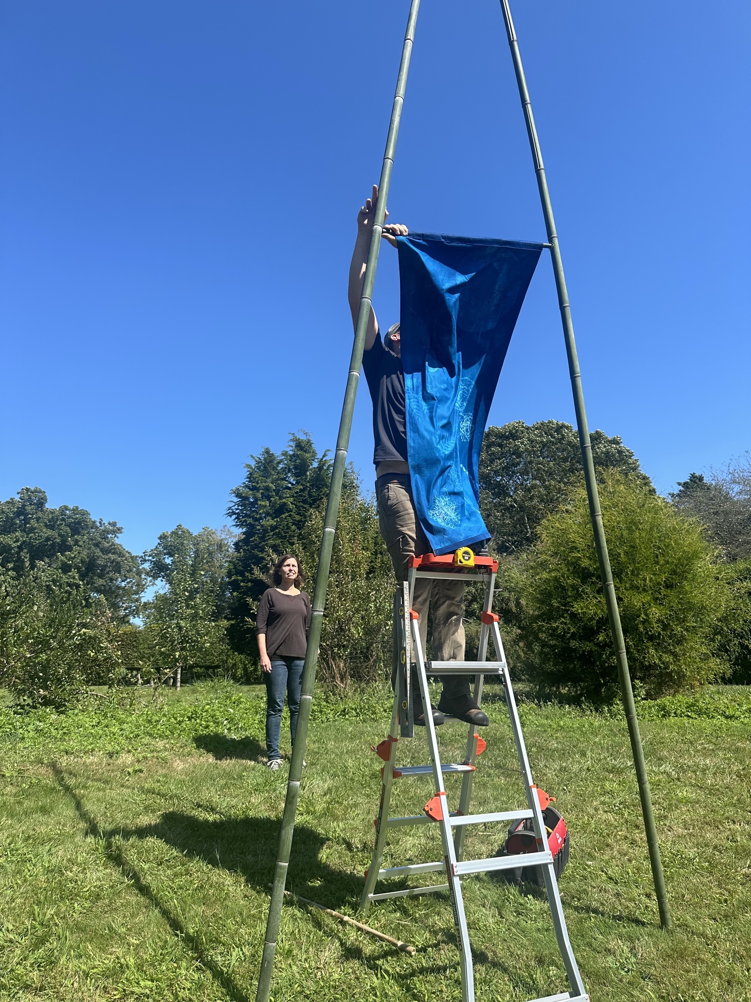 Artist Andrea Cote and her husband, Pierre, hanging her cyanotype banners at Bridge Gardens on September 9. ANNETTE HINKLE