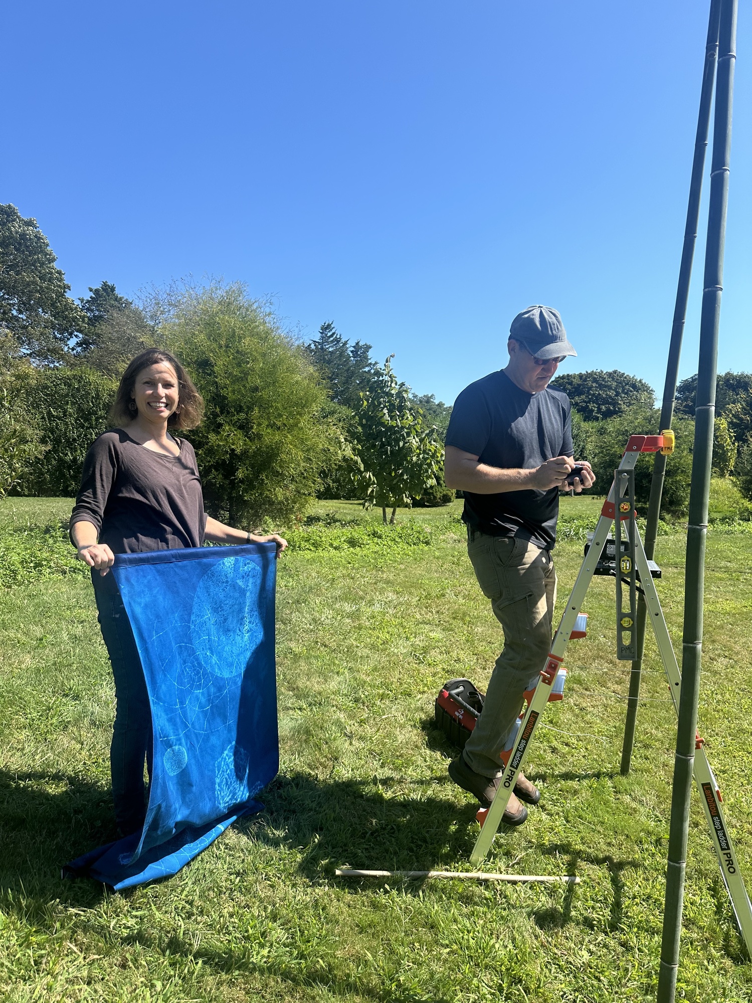 Artist Andrea Cote and her husband, Pierre, hanging her cyanotype banners at Bridge Gardens on September 9. ANNETTE HINKLE