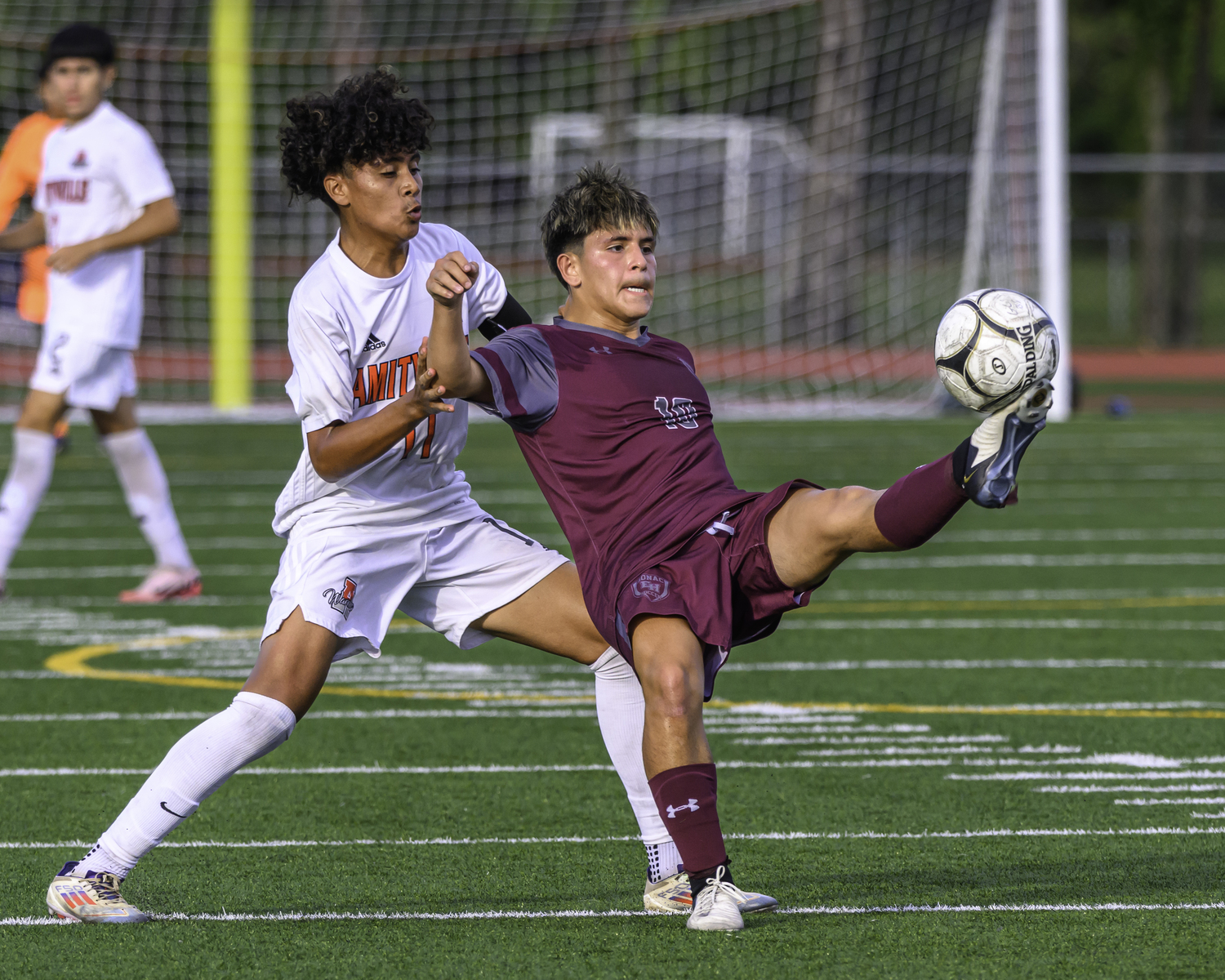 East Hampton senior Eduardo Calle plays the ball with an Amityville player on his back.   MARIANNE BARNETT