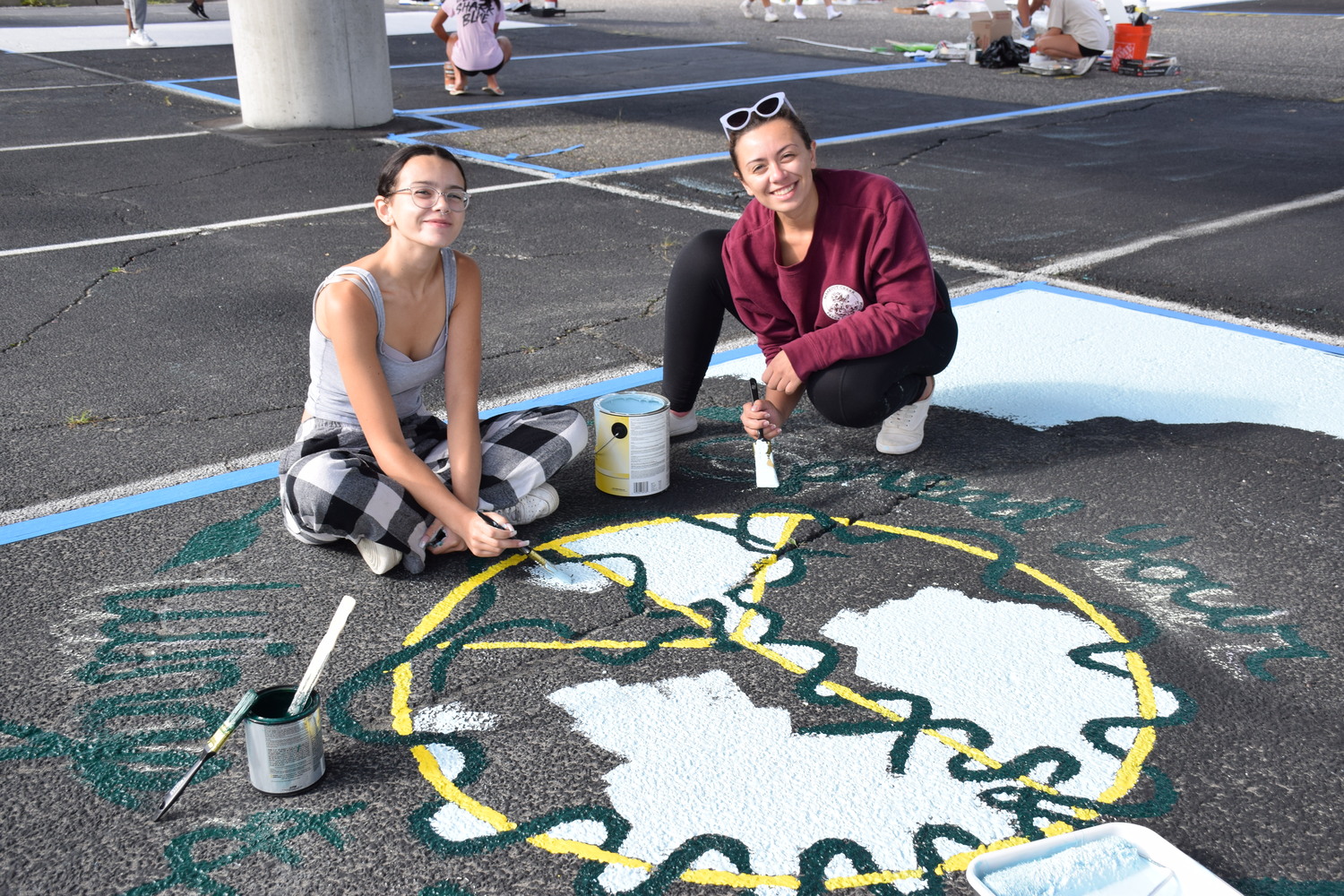 Equipped with rollers, paint brushes, stencils and paint cans, Eastport-South Manor Jr.-Sr. High School seniors, including Victoria Rivera and sister Samantha Cartwright, arrived in the early morning hours to start painting their assigned parking spaces during the school’s annual Paint Day, held on August 29. Some of the students were accompanied by peers, while others made the activity a family affair.    COURTESY EASTPORT-SOUTH MANOR SCHOOL DISTRICT