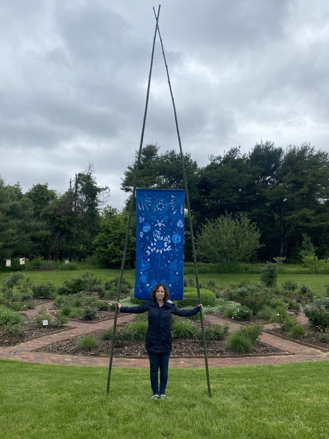 Artist Andrea Cote with a prototype of one of her cyanotype banners installed at Bridge Gardens. COURTESY THE ARTIST