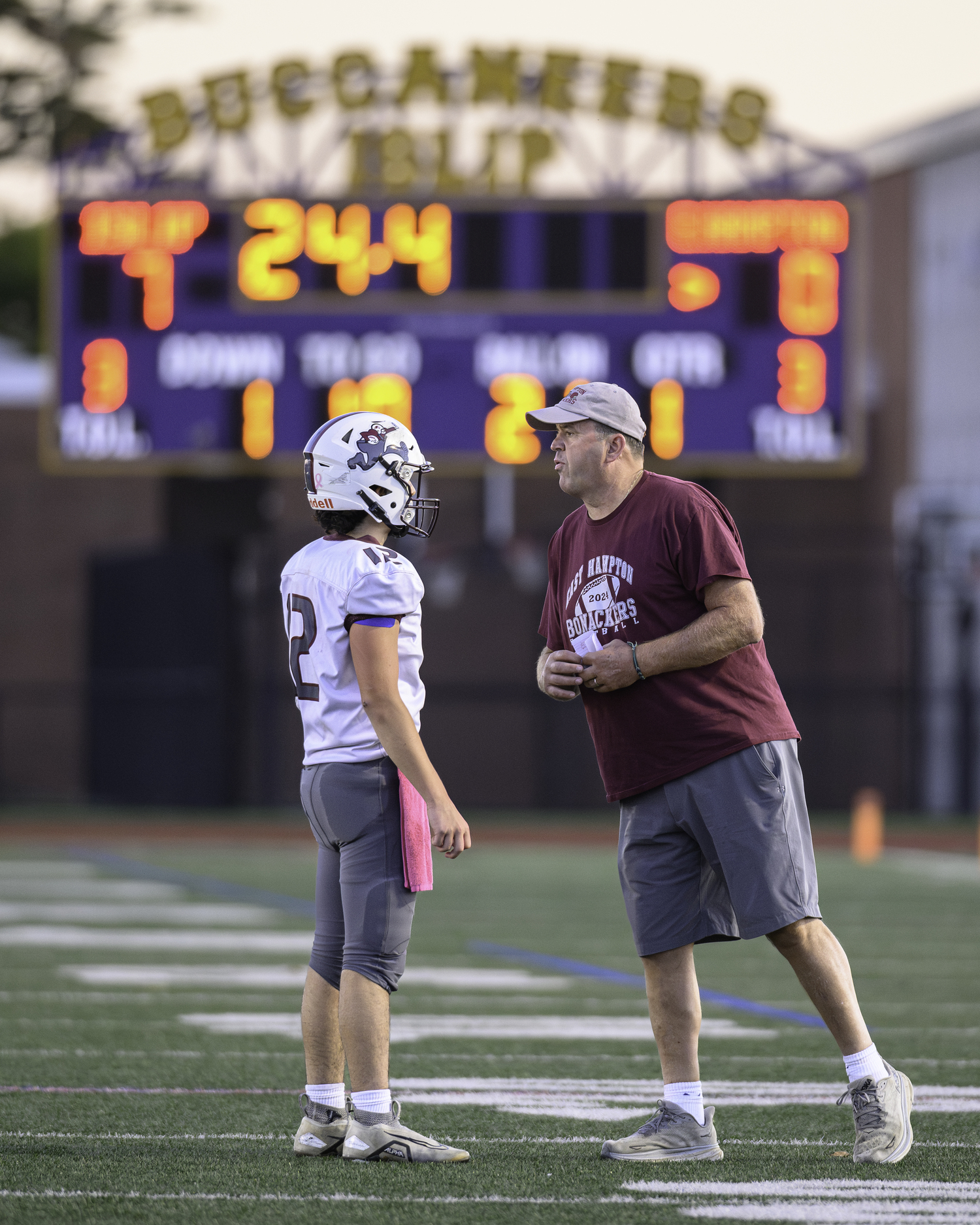 East Hampton head coach Joe McKee gives quarterback Theo Ball a play late in the first quarter of Saturday evening's game.   MARIANNE BARNETT