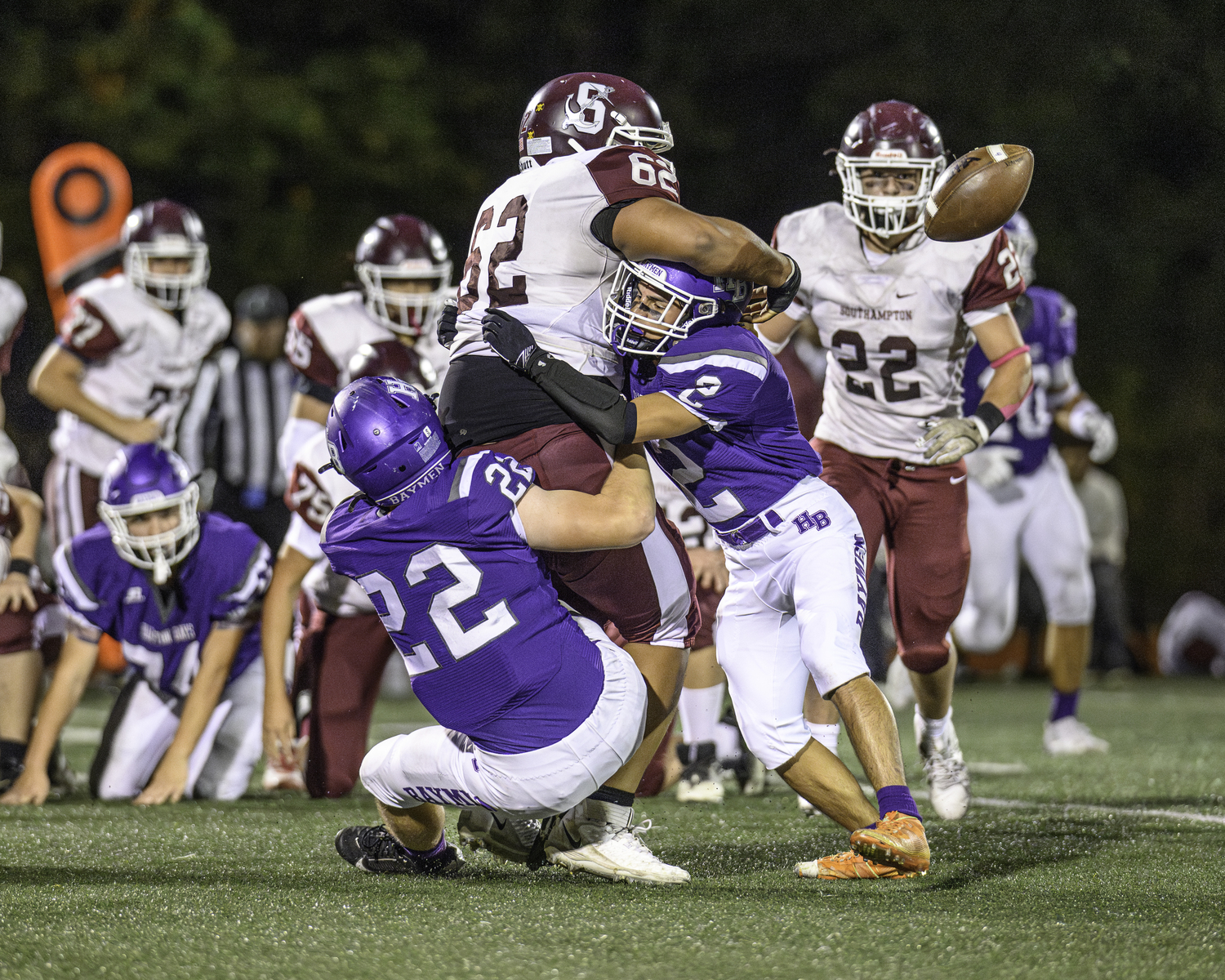 Hampton Bays senior Nate Donahue (22) and Kevin Saa Pacheco team up to take down Southampton senior Jackson Garcia and force a fumble.   MARIANNE BARNETT