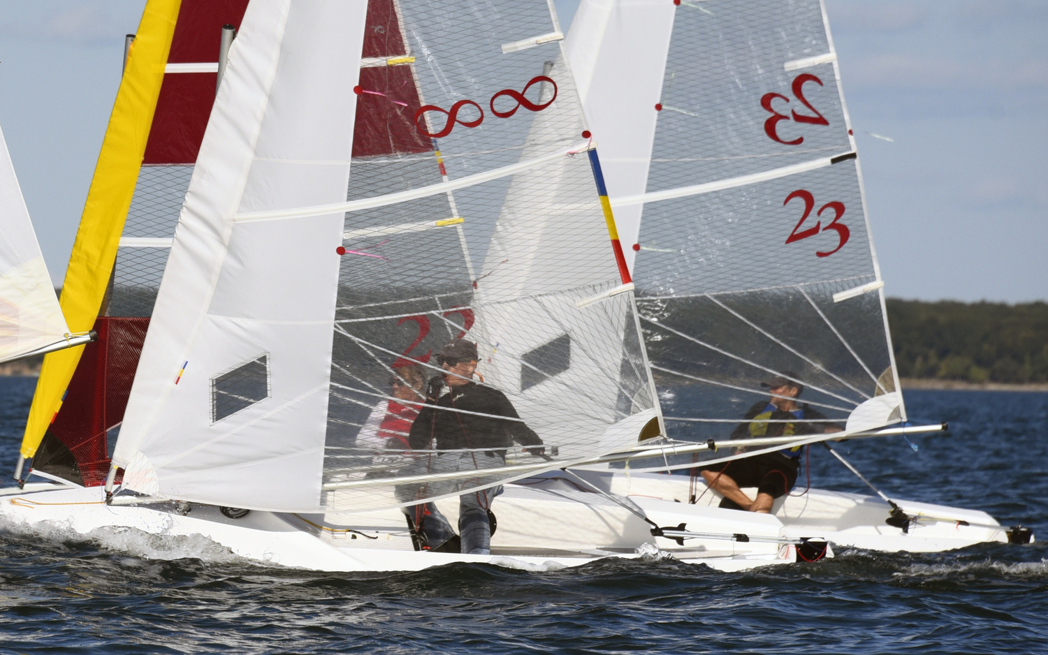 The soft-focus created by translucent sails doesn’t lessen the intensity on the faces of Barbara-Jo Howard, left, James Merrell and Gloria Frazee as they drive hard toward the weather mark.   MICHAEL MELLA