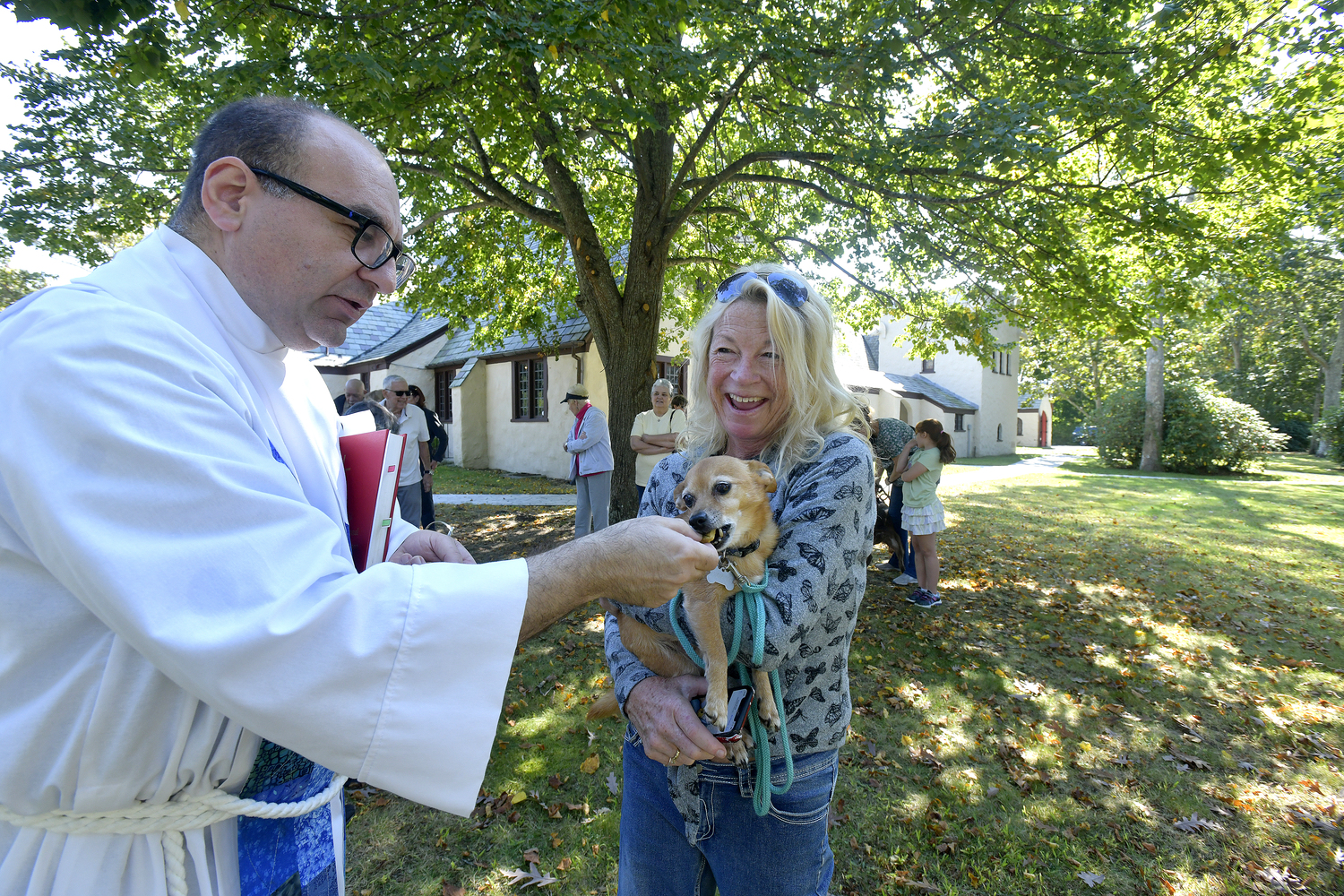 The Rev. Justin A. Falciani, Rector at St. Mary's Episcopal Church in Hampton Bays, blesses Brutus and his human, Kelly Gibson, on Saturday to honor St. Francis with the Blessing of the Animals.    DANA SHAW