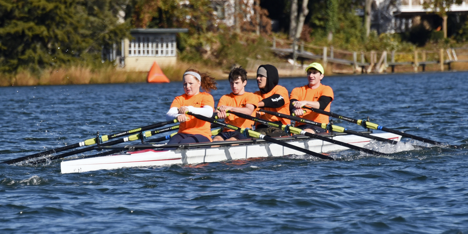 In the final race that ultimately put Team Orange into overall first place seconds ahead of Team Pink, bowman Andrew Orme steers the boat and calls out the stroke pace timing, while red-haired Venetia Satow’s stroke into the water is what the other three oarsmen follow. Sebastian Corson is in seat two in front of Andrew and Luke Shannon in seat 3. These two middle oarsmen are considered the engine room on a quad scull.  MICHAEL MELLA