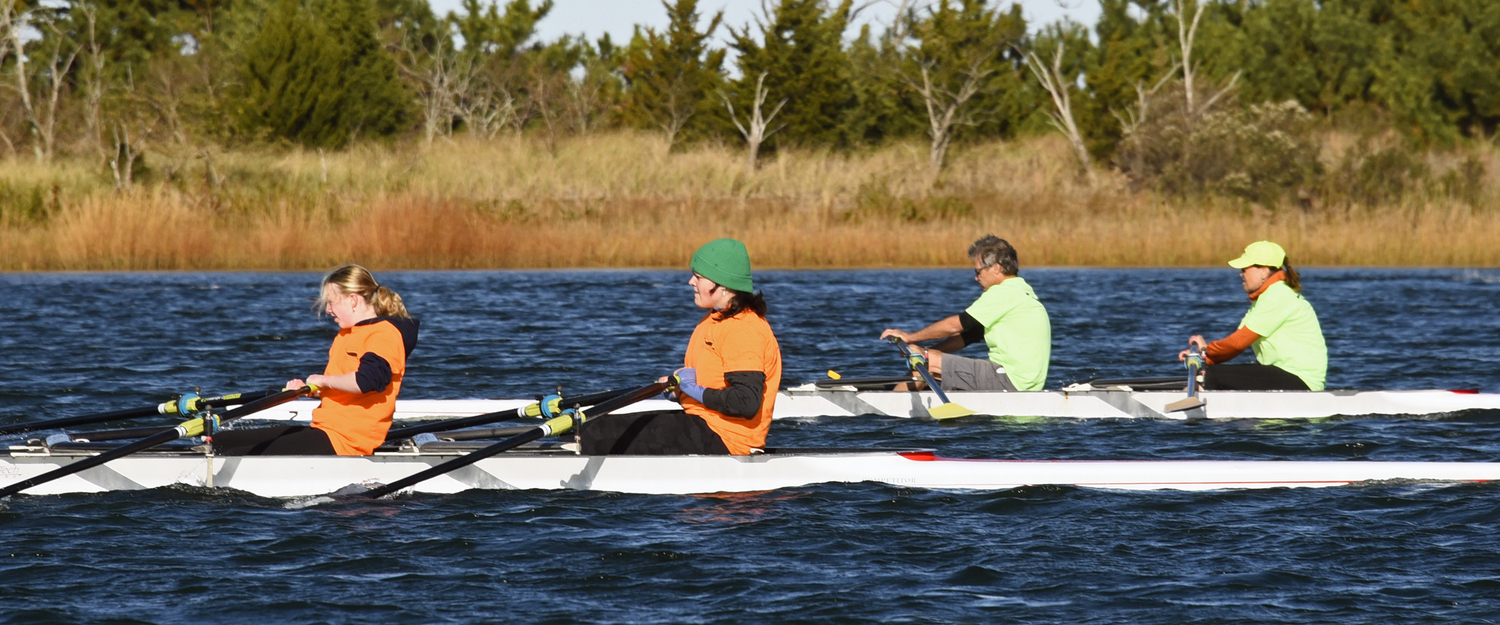 Two of the nine rowers on the first place Team Orange working their way up on third place Team Green. The reeds and evergreens in the background separate this body of water, Sag Harbor Cove, from Long Beach’s Noyack Bay.  MICHAEL MELLA