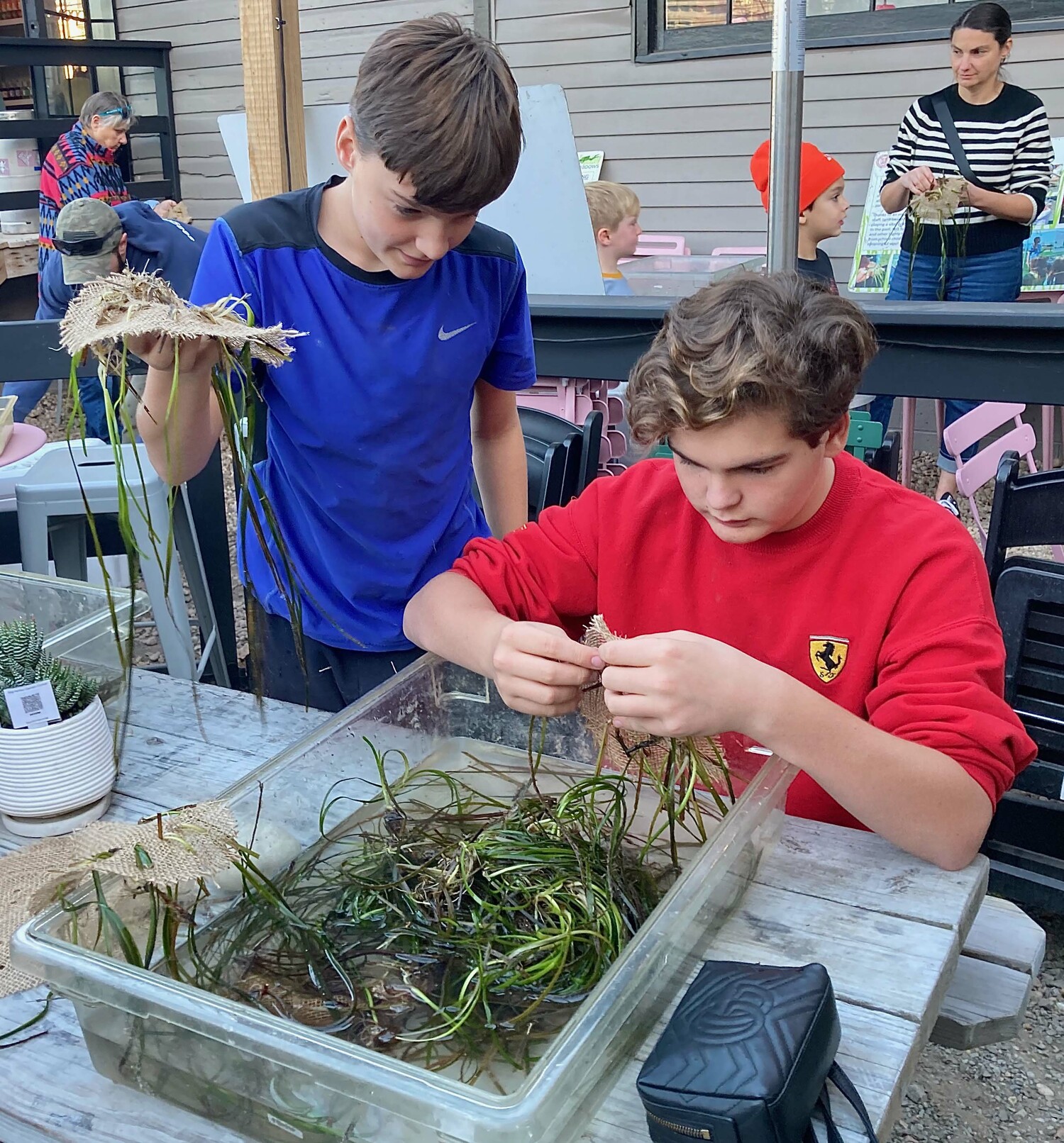 Hunter and Zeke Malpass weave eelgrass discs for planting in local water at an eelgrass workshop with Cornell Cooperative Extension on Friday at Kidd Squid Brewing Company in Sag Harbor on Friday.   KYRIL BROMLEY