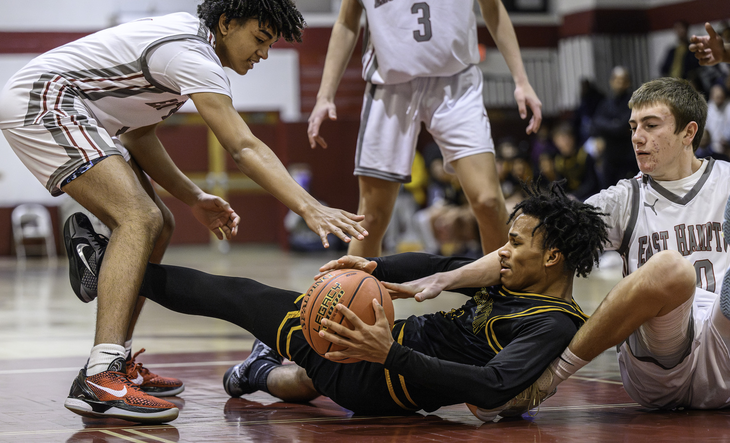 Bridgehampton junior Jai Feaster gets to a loose ball with a trio of East Hampton players surrounding him.  MARIANNE BARNETT