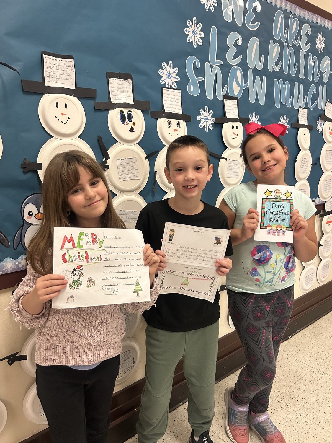 Hampton Bays Elementary School students recently spent time penning holiday cards to Hampton Bays alumni who are serving in the military. Cards will be sent to Korea, Qatar and Washington state, among other places. Students also made cards for patients at the local VA hospital. From left, Evey Kirst, Jaiden Karl and Niamh Kelly. COURTESY HAMPTON BAYS SCHOOL DISTRICT