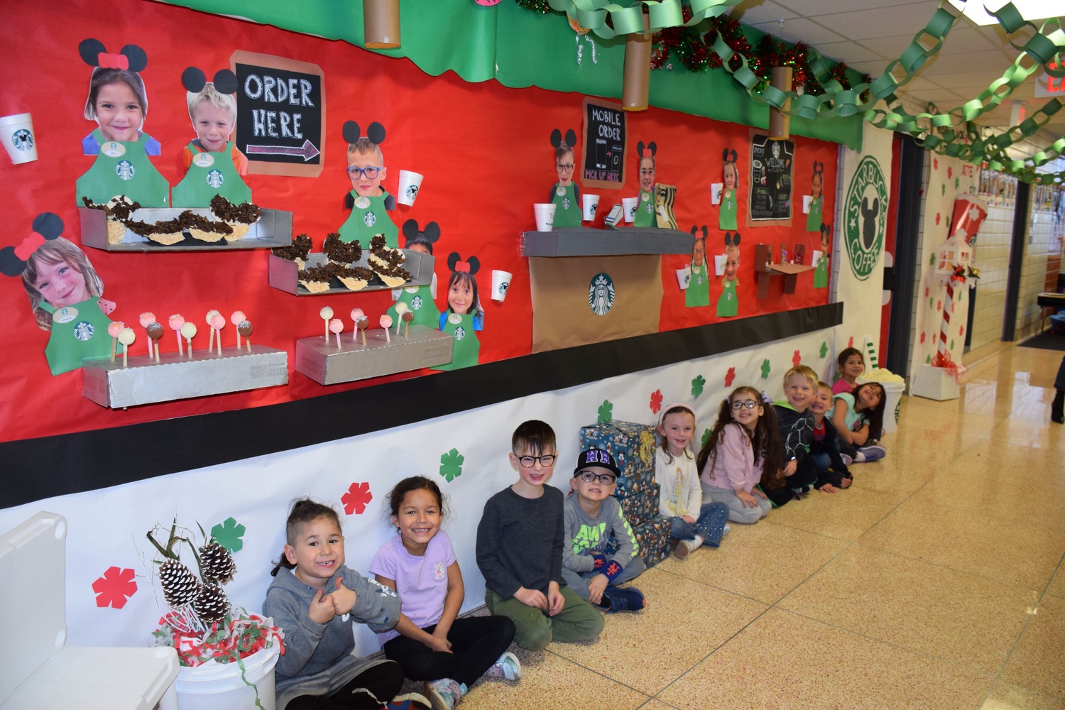 The kindergarten hallway at Hampton Bays Elementary School has been transformed into a holiday wonderland with a theme of Downtown Disney. Teachers and their students worked to bring the vision to life over the past several weeks. Each class created elaborate displays outside their classroom that depict shops from Downtown Disney. There is a Starbucks, Mini Mouse bake shop, Pineapple Dole Whip shop, art and clock stores among others. Students dressed in their holiday best on December 11 to celebrate the completion of the hallway. COURTESY HAMPTON BAYS SCHOOL DISTRICT